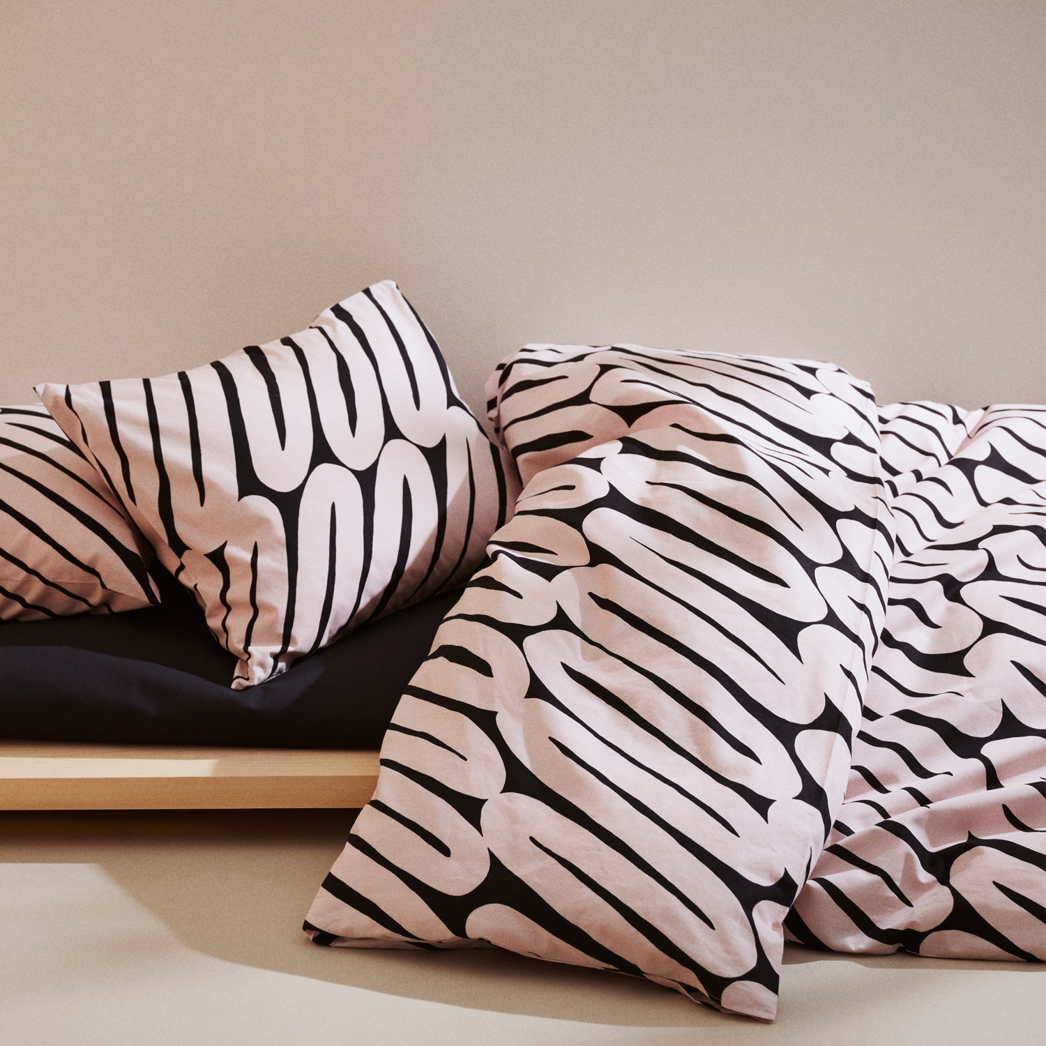 Laskos black and beige patterned pillows and duvet on a bed