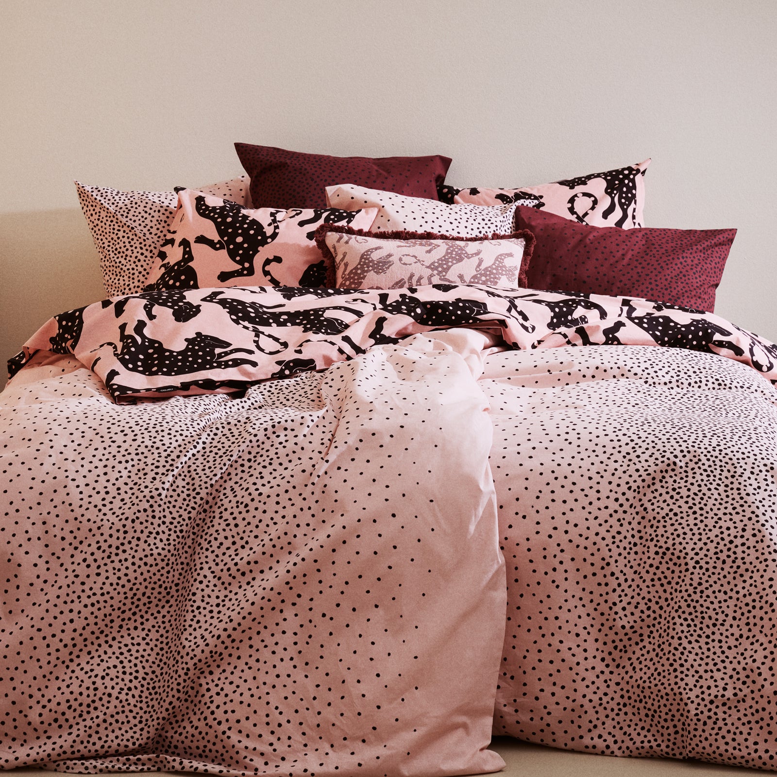 Bed with Täplä and Leonora bedding and pillows against a neutral wall