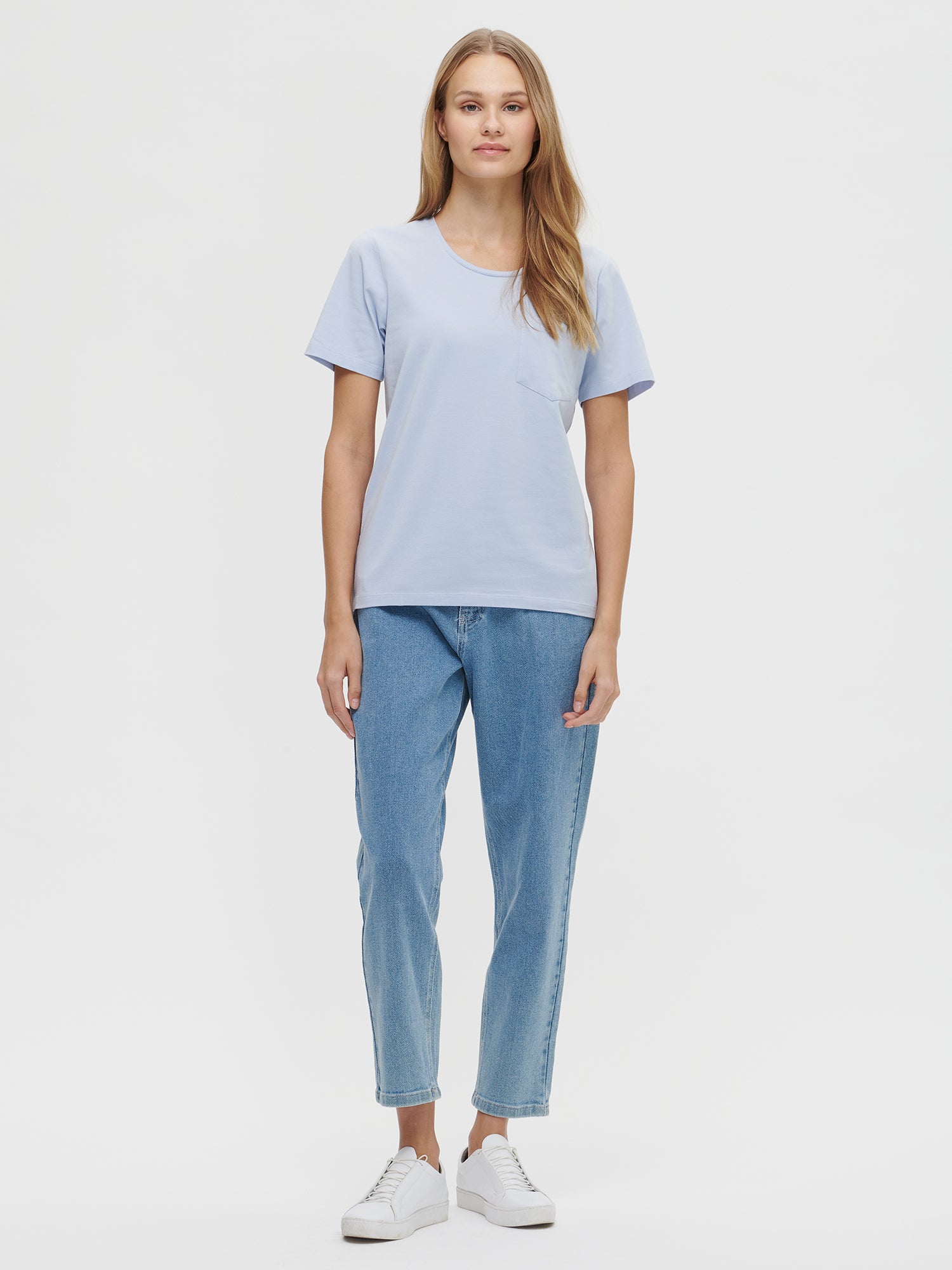 This elegant light blue Tasku t-shirt for women features a round neckline. A classic t-shirt is a reliable choice for any outfit, with its effortless versatility. Worn by a model in size S.