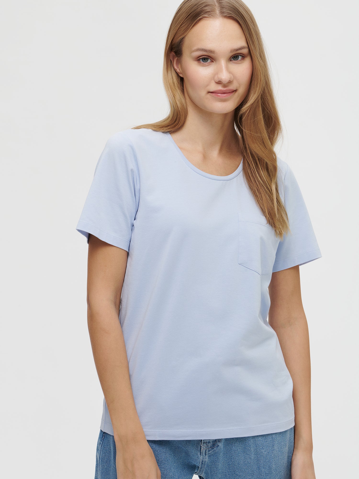 This elegant light blue Tasku t-shirt for women features a round neckline. A classic t-shirt is a reliable choice for any outfit, with its effortless versatility. Worn by a model in size S.