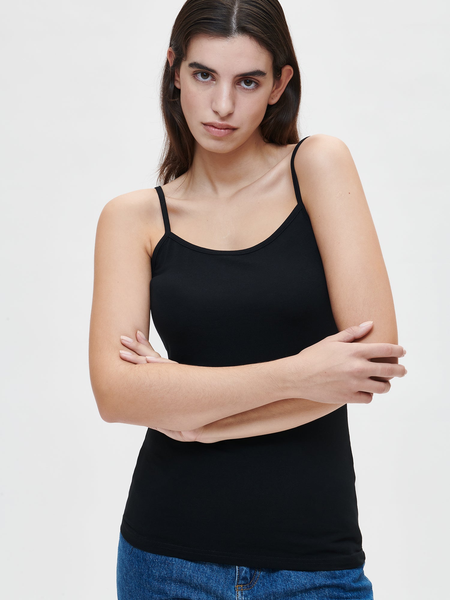Nanso women's high quality black Basic top with thin straps crafted from soft, stretchy cotton-elastane knit, on a model with jeans pictured from the front, close-up.