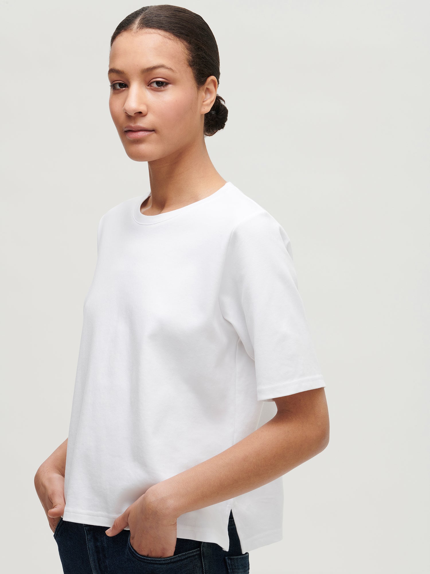 Nanso women’s white loose fit T-shirt from 100 % cotton, on a model from the side.