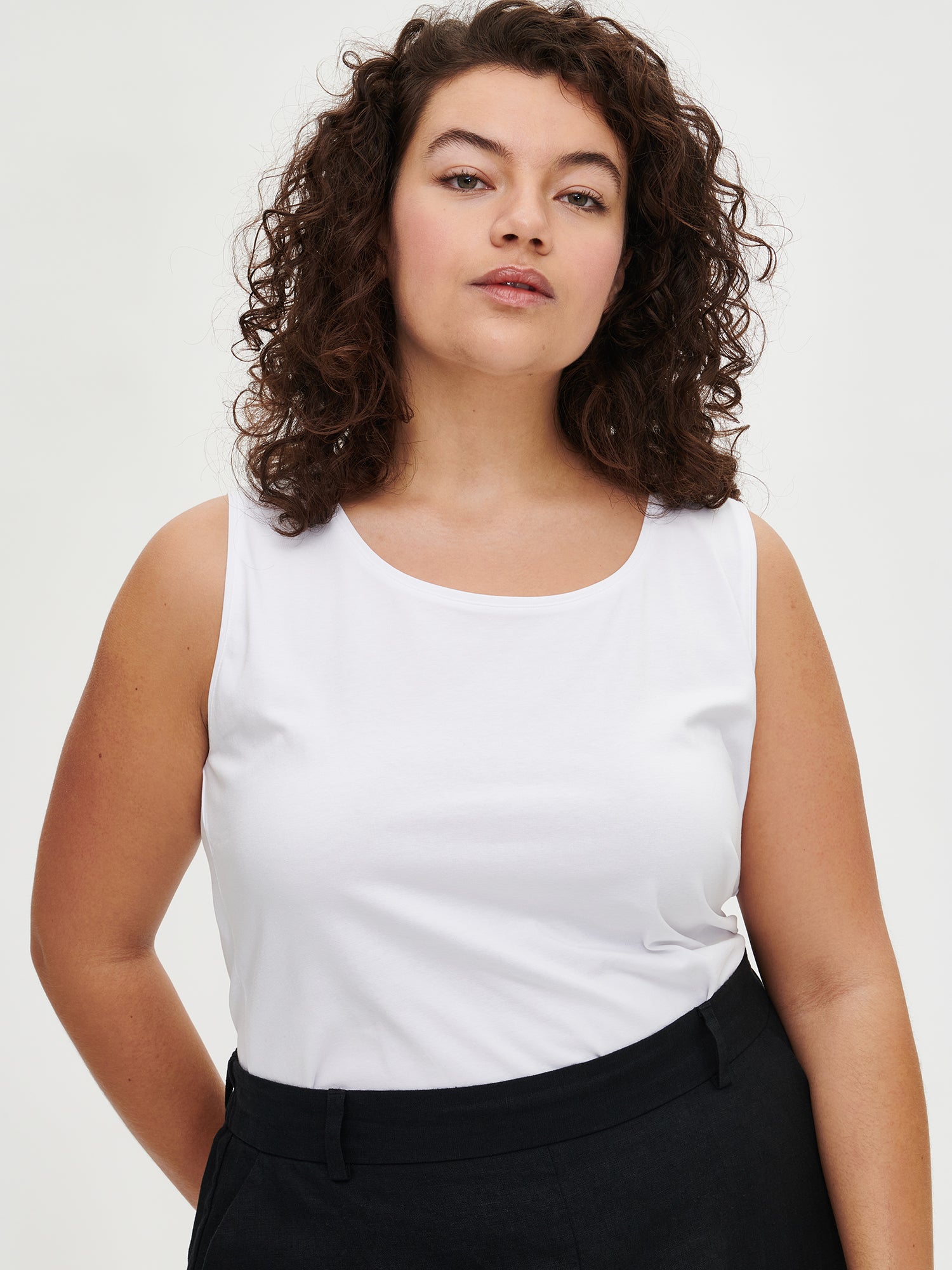 Nanso women's white Basic top with comfortable wide straps and a timeless silhouette. Crafted from soft, stretchy organic cotton-elastane knit. On a plus size model from the front, close up.