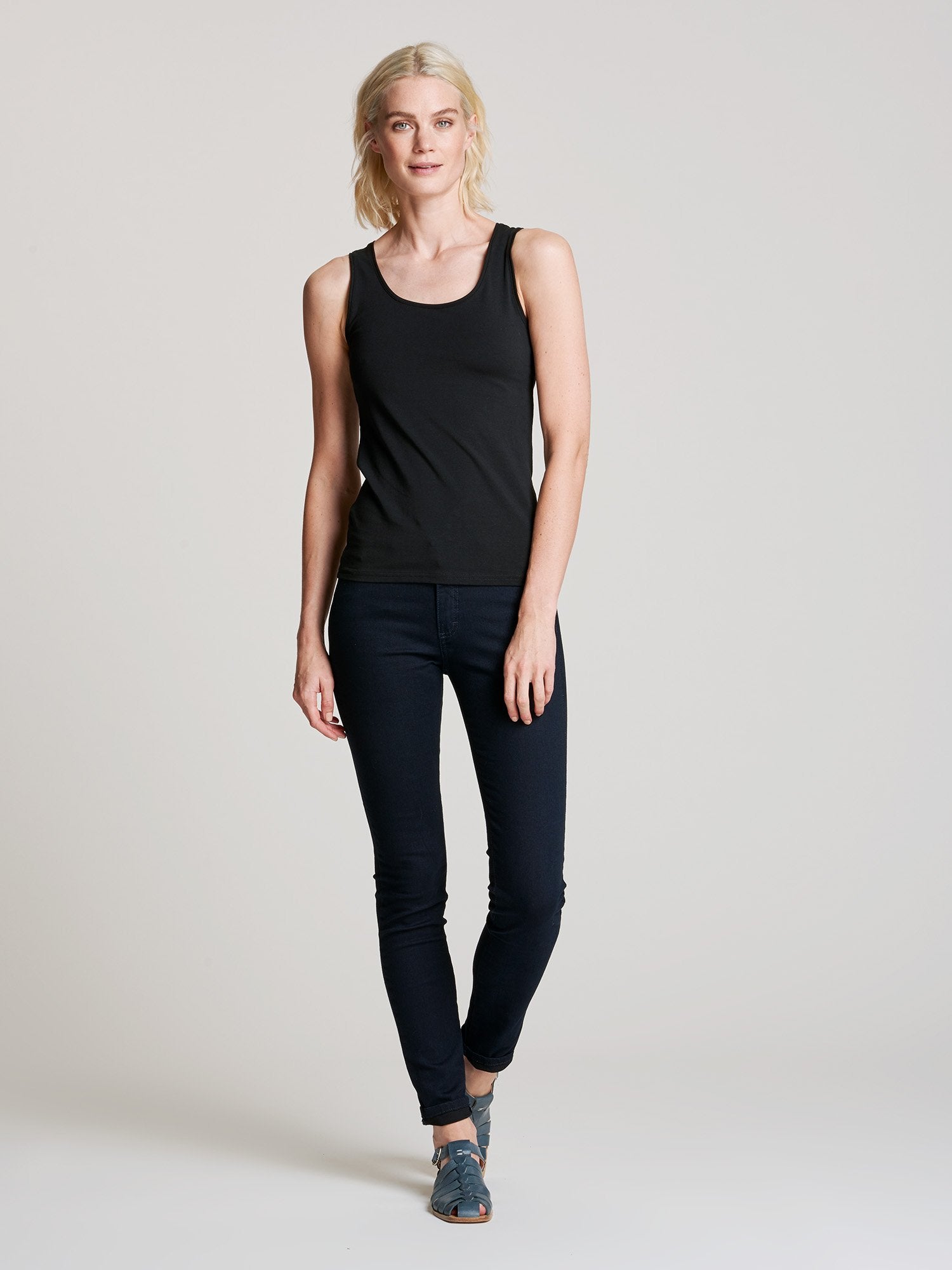 Nanso women's black Basic top with comfortable wide straps and a timeless silhouette. Crafted from soft, stretchy organic cotton-elastane knit. On a model with jeans.