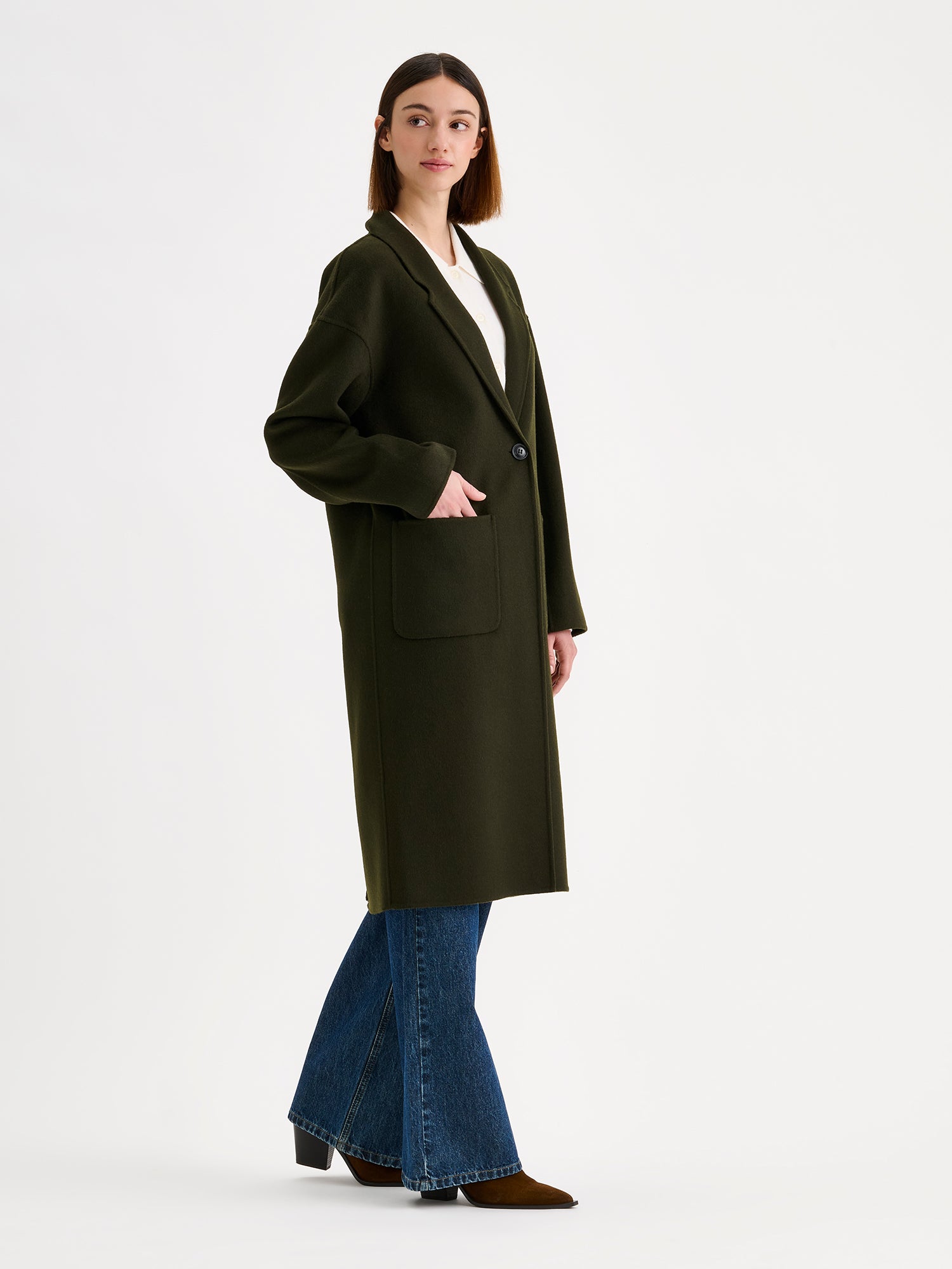 Nanso women's stylish and timeless olive green YLLE wool coat on a model with a white collared cardigan and jeans