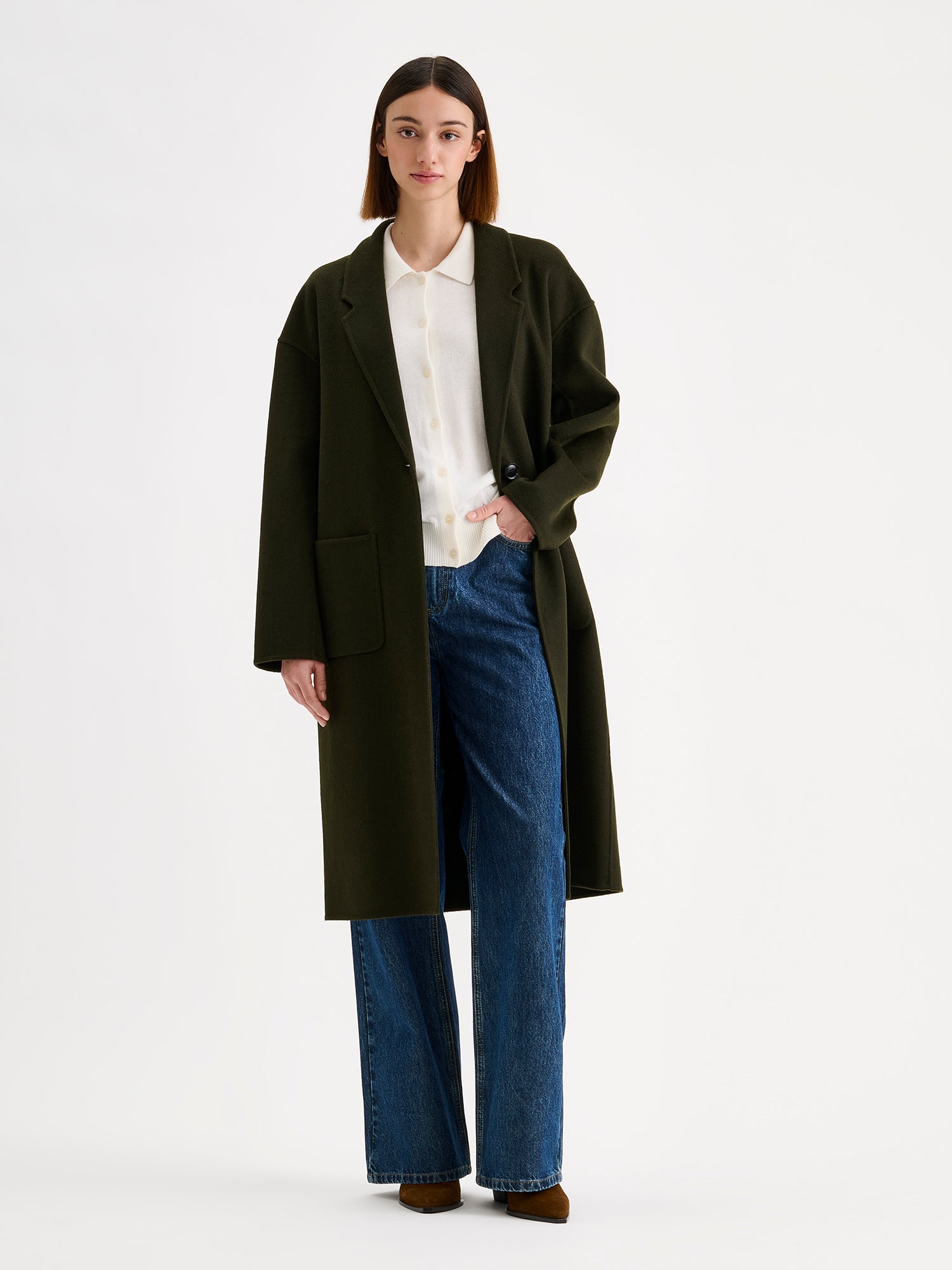 Nanso women's stylish and timeless olive green YLLE wool coat on a model with a white collared cardigan and jeans