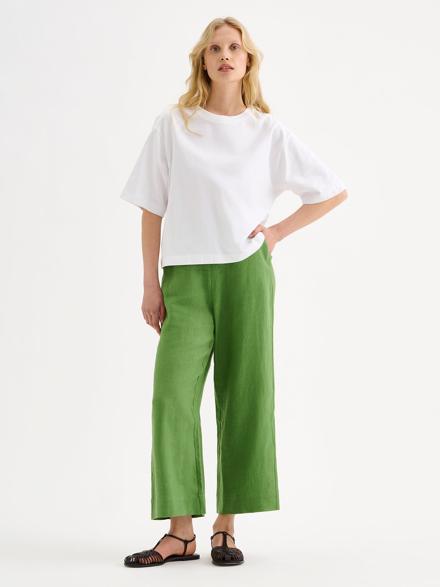 Nanso SAARI linen culottes with elasticated waist and side pockets in a vibrant green shade on a model with a white t-shirt.