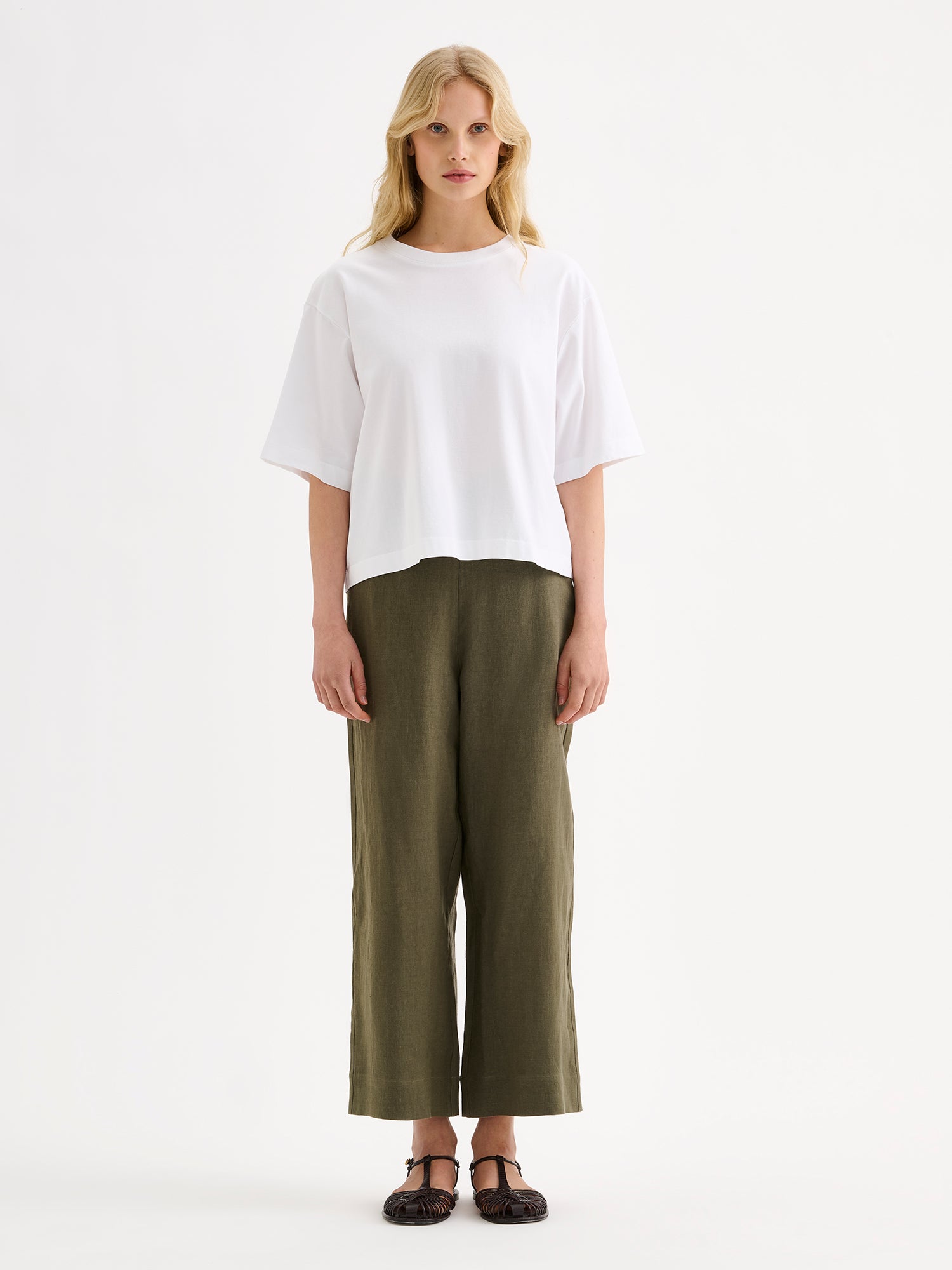 Nanso SAARI linen culottes with elasticated waist and side pockets in a sophisticated olive green shade on a model with a white t-shirt.