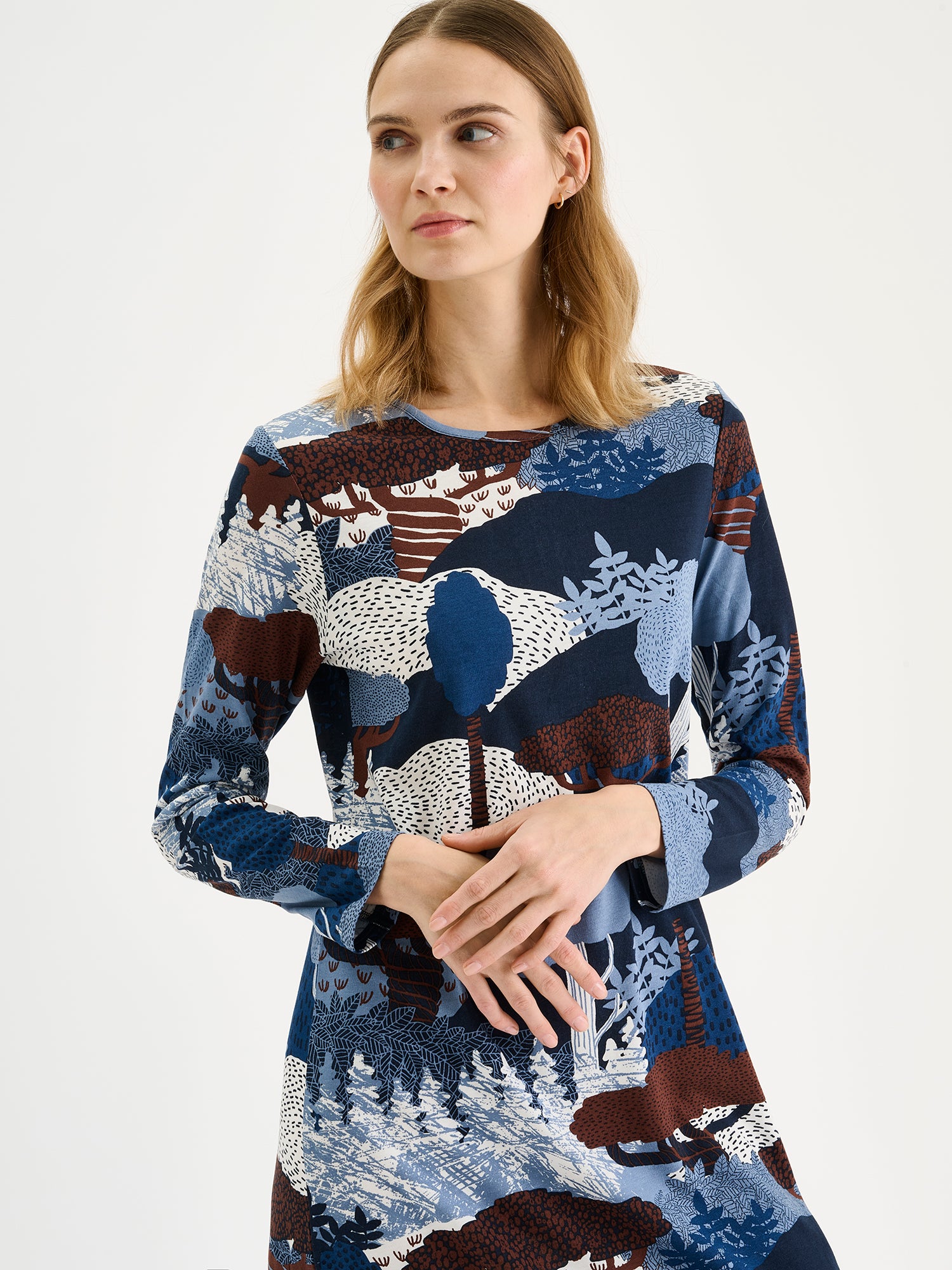 Nanso women's long Ruska nightgown features a beautiful nature-inspired print in harmonious shades of blue and brown. Pictured on a model, close-up.