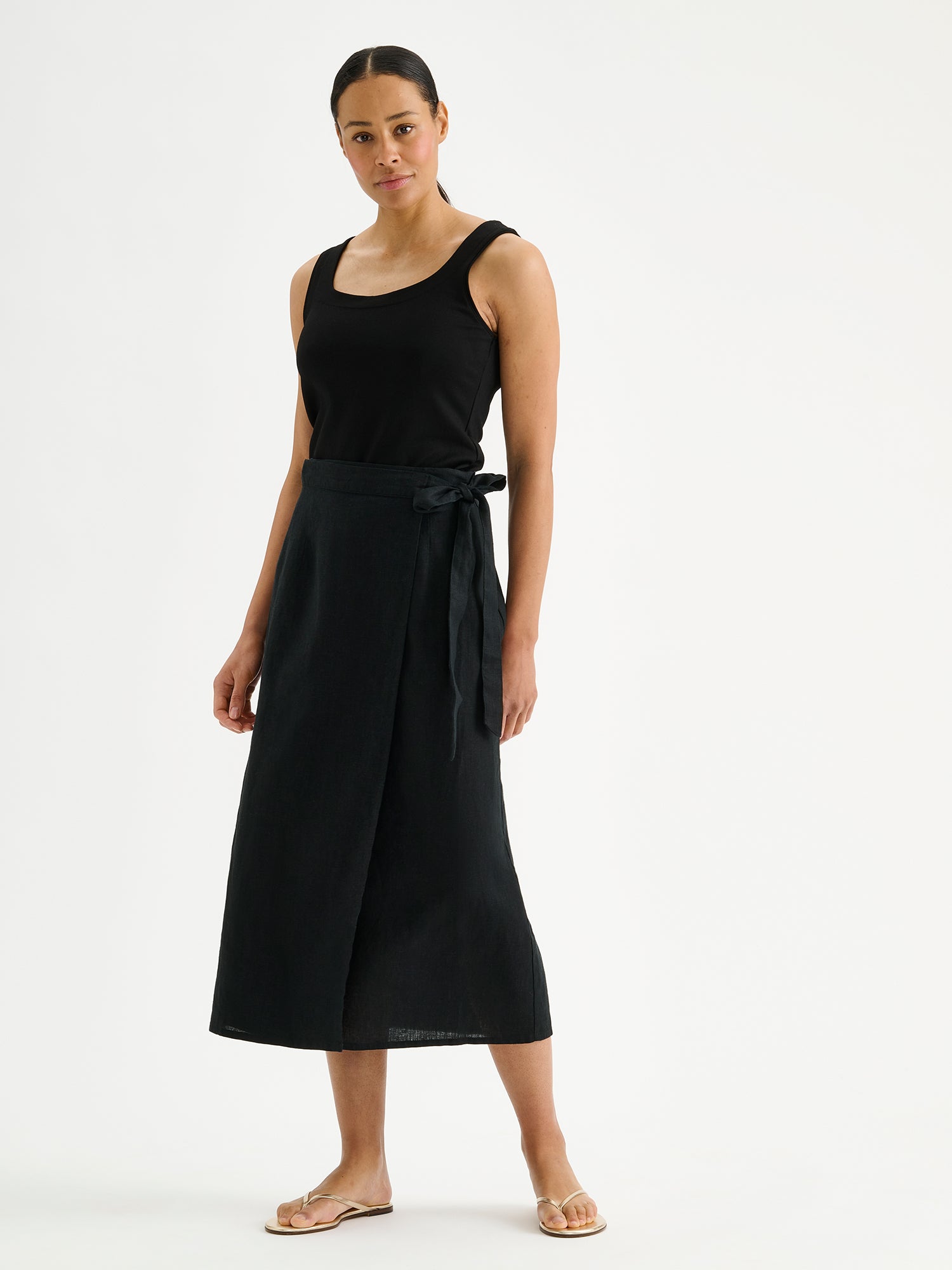 Nanso women's elegant black wrap-style Liine linen skirt on a model with a black top and sandals.