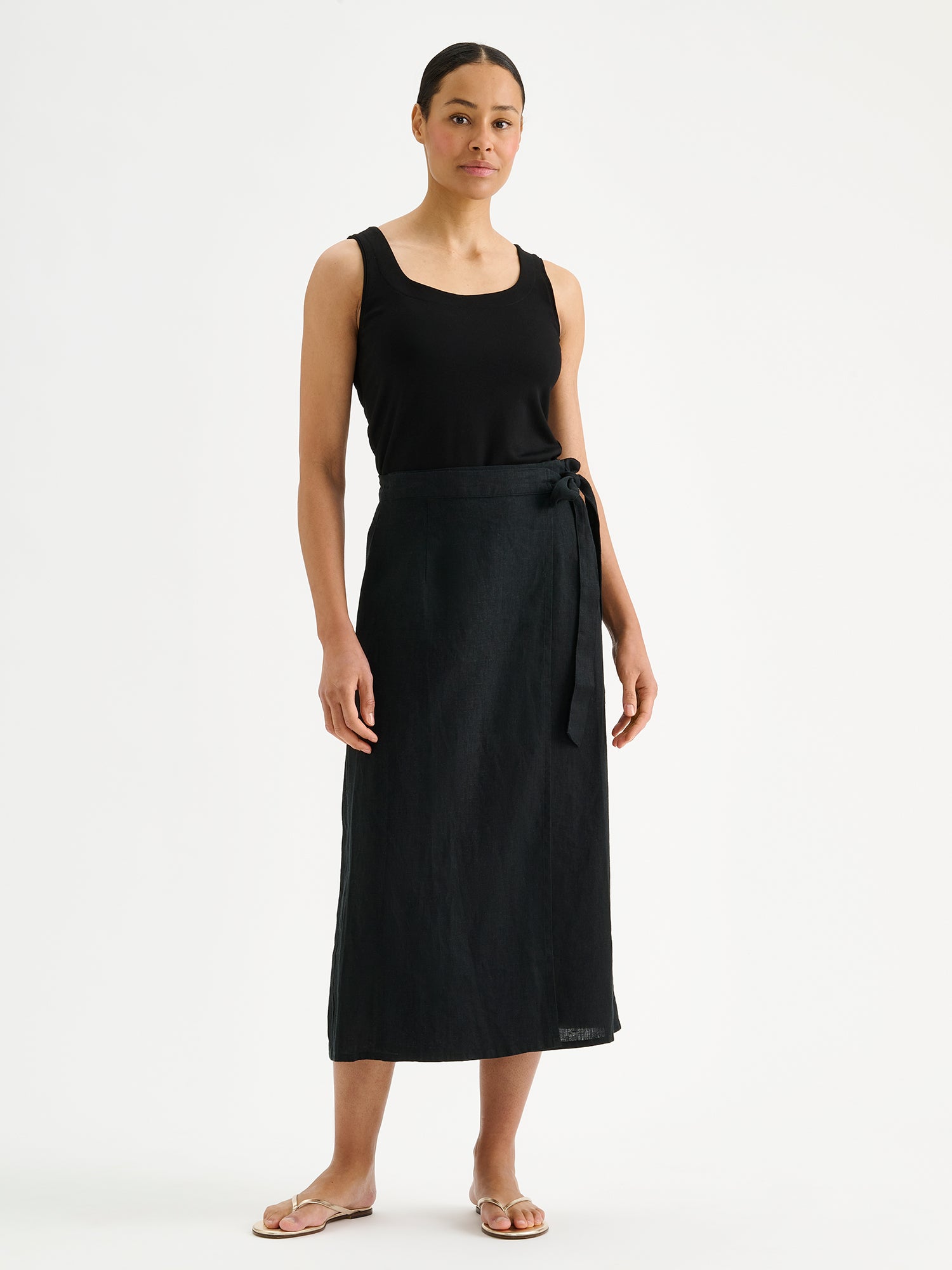 Nanso women's elegant black wrap-style Liine linen skirt on a model with a black top and sandals.