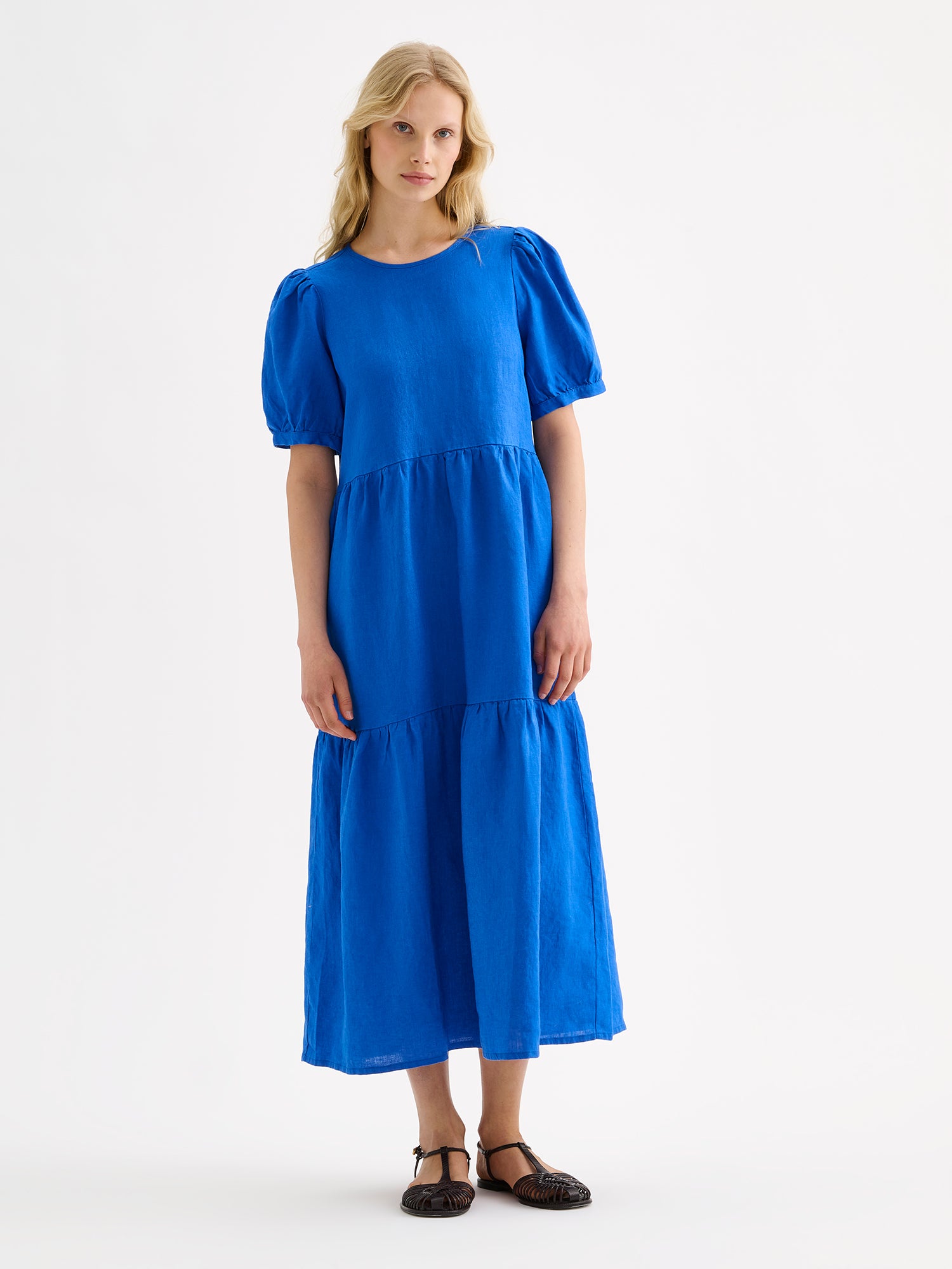 The Sarastus long blue dress for women is made of high-quality, durable, and breathable woven linen fabric, on a model with sandals.