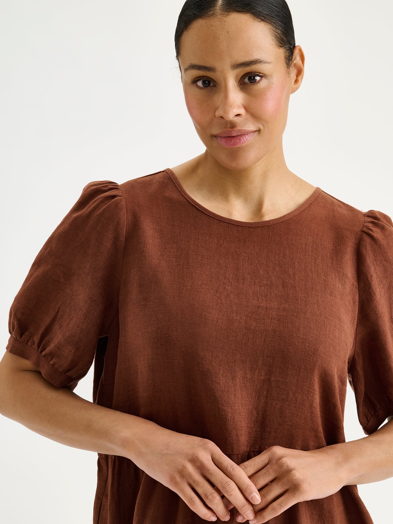 The Sarastus long brown linen dress with voluminous frill layers and short puff sleeves on a model, close-up.