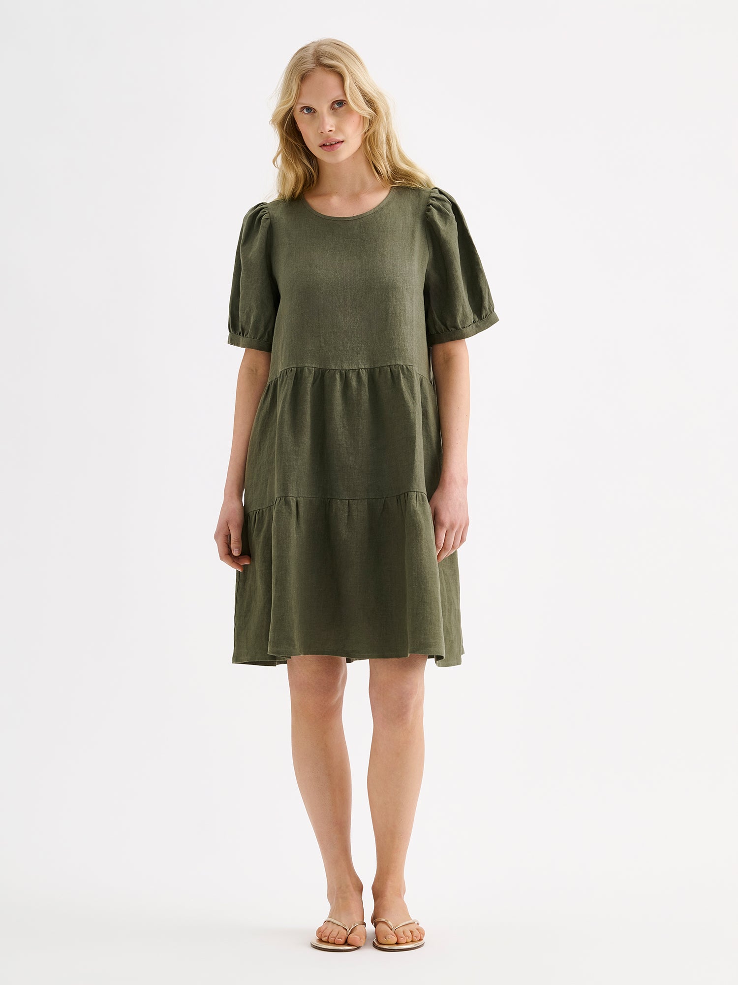 Nanso women's beautiful olive green Sarastus linen dress with voluminous frill layers and short puff sleeves on a blonde model.