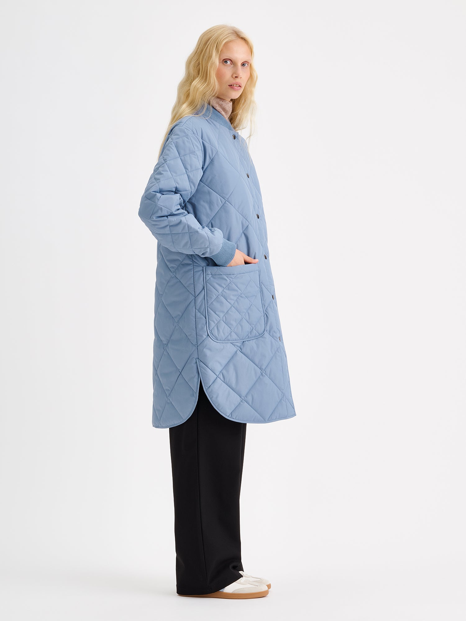 Nanso women's casual Midi quilted coat in smoky blue on a model with black jeans from the side angle.