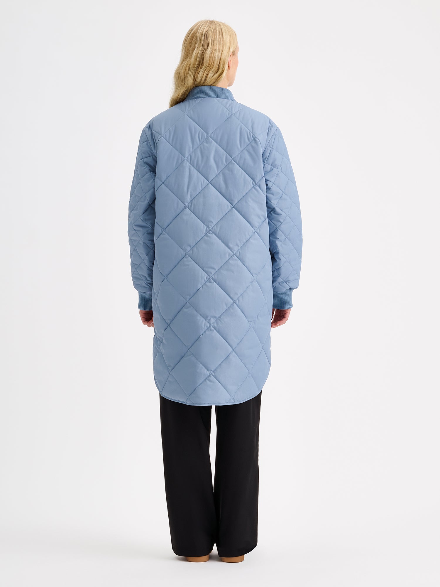Nanso women's casual Midi quilted coat in smoky blue on a model with a black jeans from the backside.