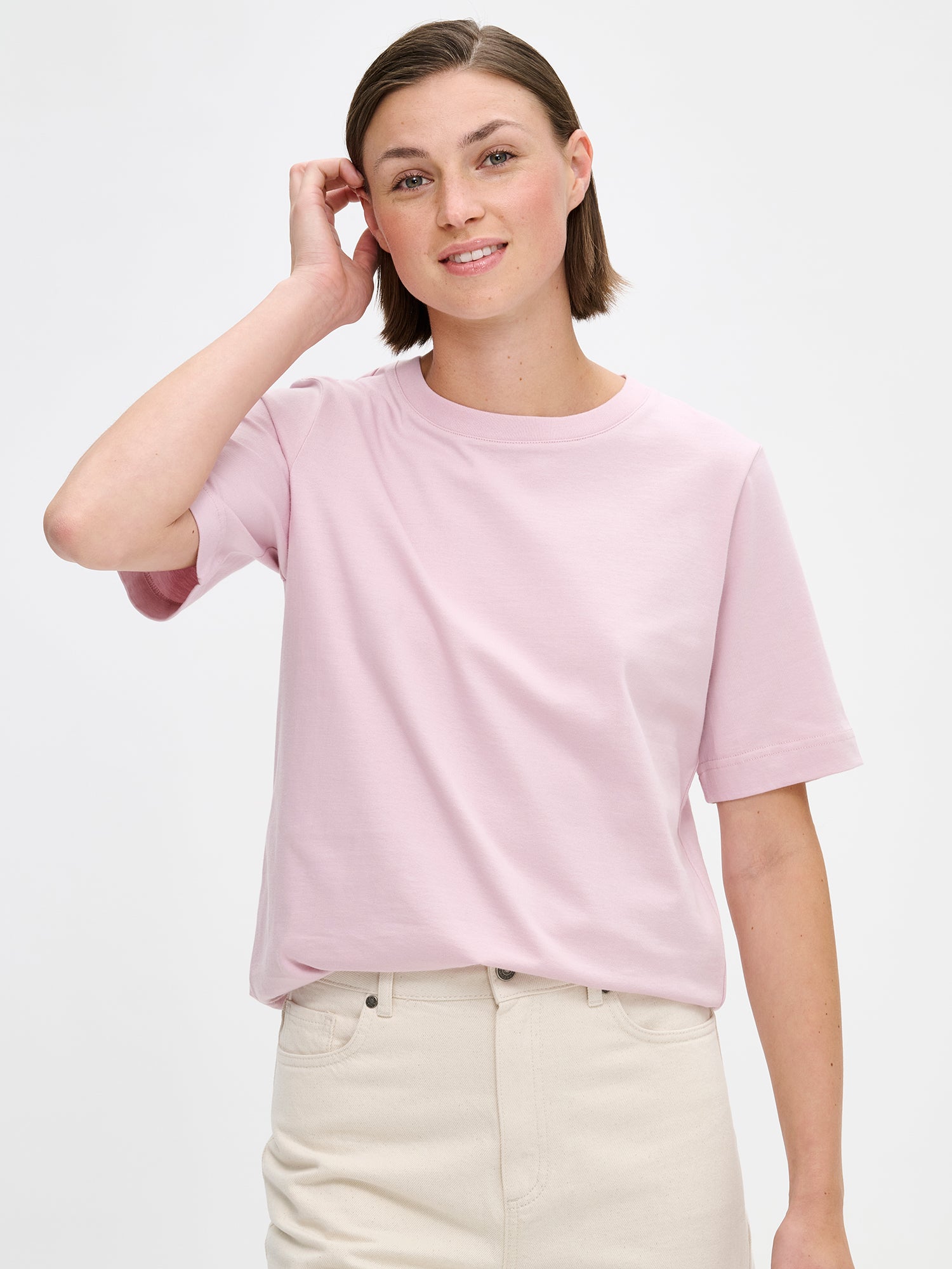 Women's Normi T-shirt in Pink with relaxed fit and straightforward silhouette. The material is 100% high-quality organic cotton, which maintains its quality over time. Pictured on a model with jeans, close-up.