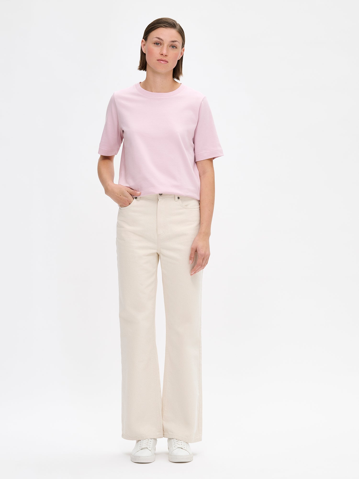Women's Normi T-shirt in Pink with relaxed fit and straightforward silhouette. The material is 100% high-quality organic cotton, which maintains its quality over time. Pictured on a model with jeans.