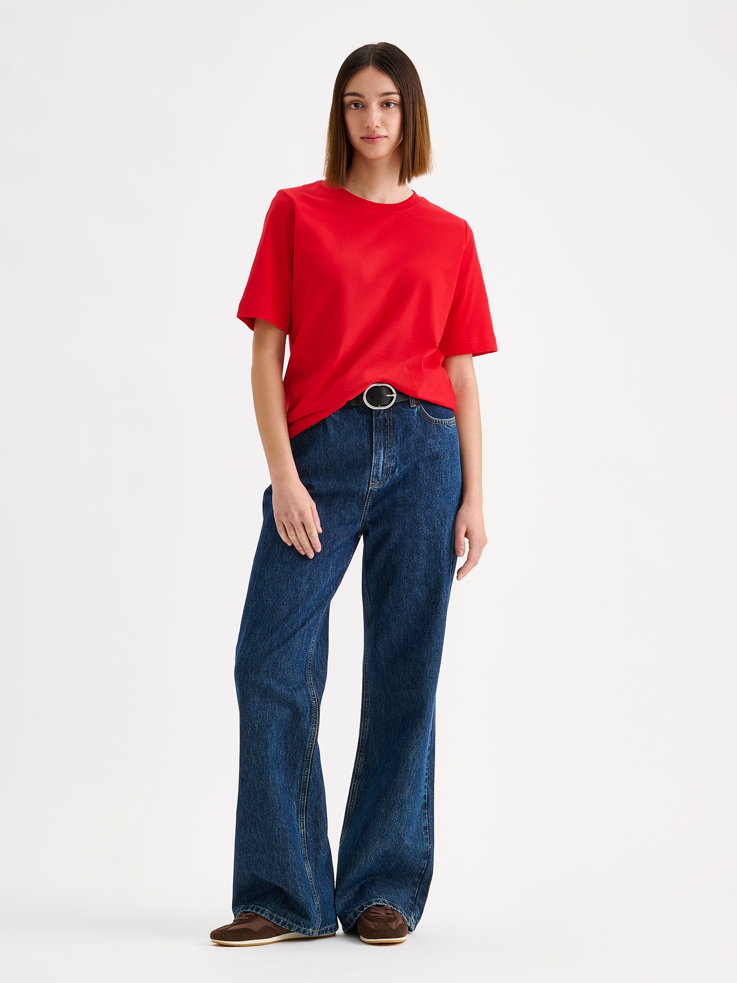 Women's Normi T-shirt in Red with relaxed fit and straightforward silhouette, on a model with blue wide jeans.