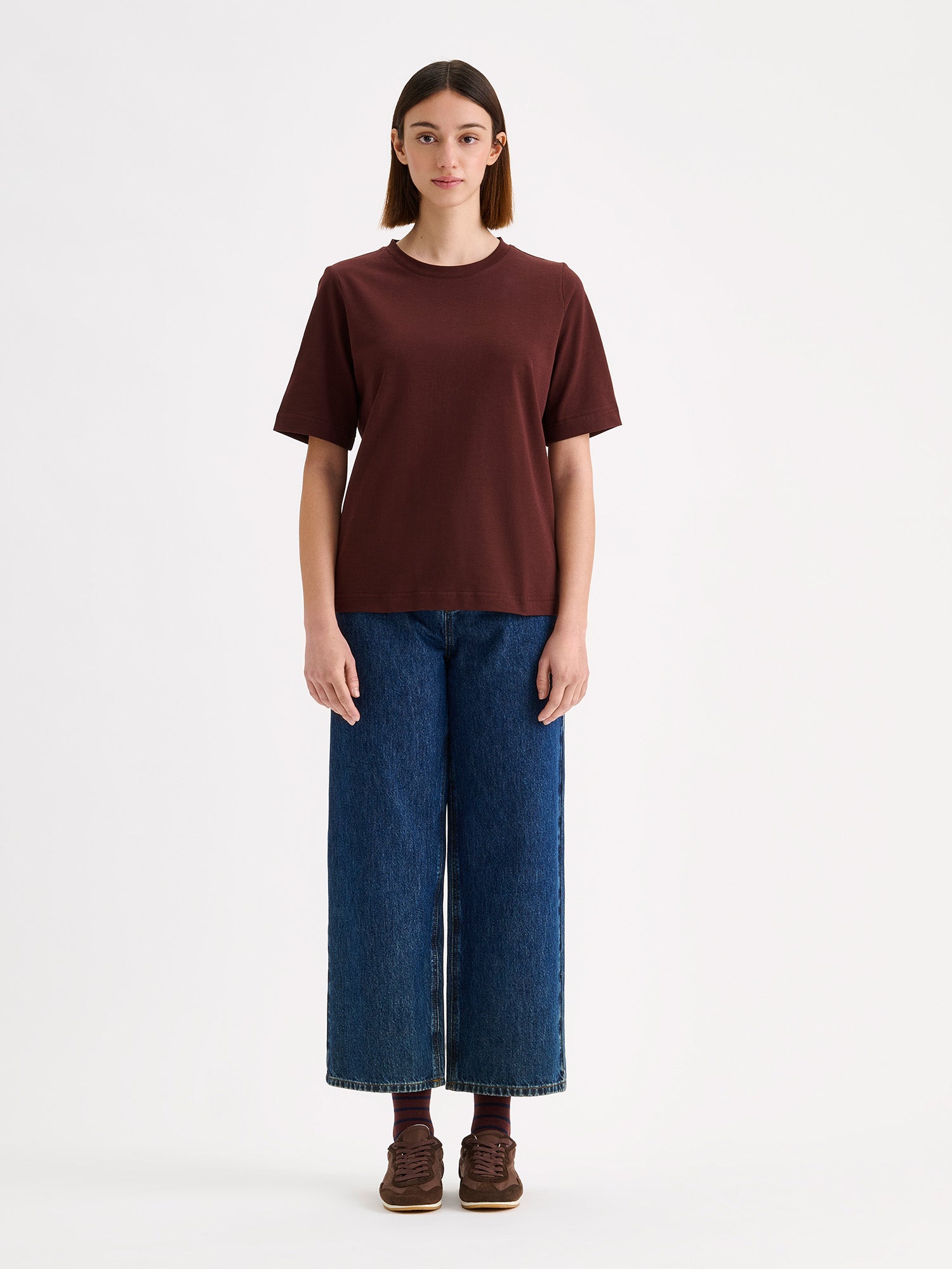 Women's Normi T-shirt in Dark Brown with relaxed fit and straightforward silhouette, on a model with blue cropped jeans.