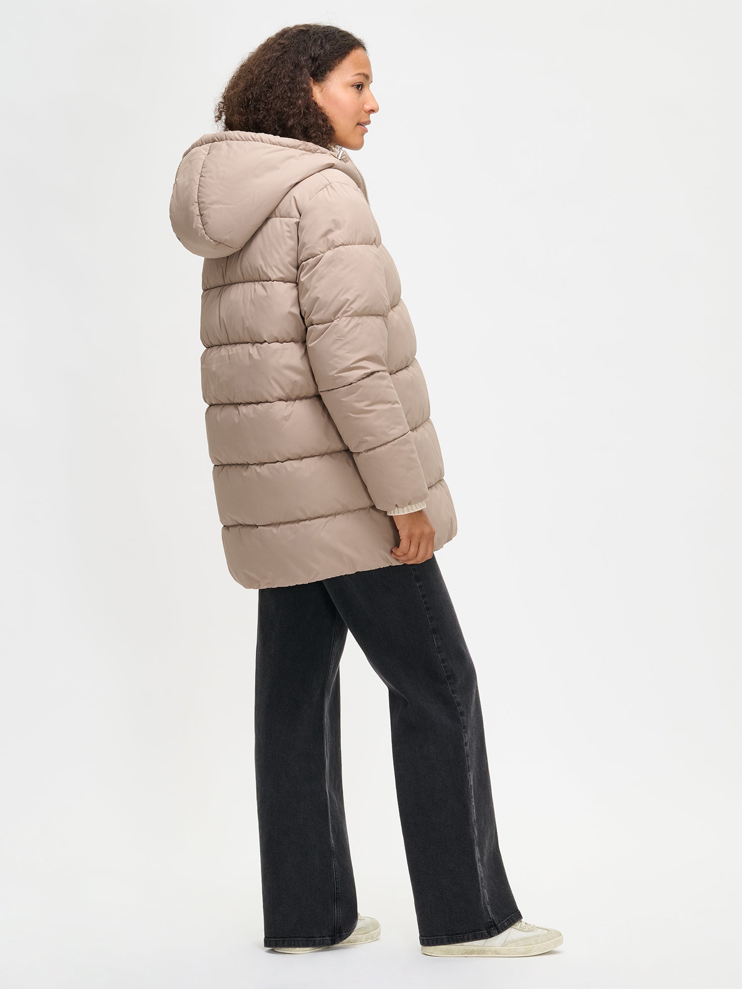 The beige Lumi padded coat provides warmth with its soft, lightweight padding and generous fit. From the back.
