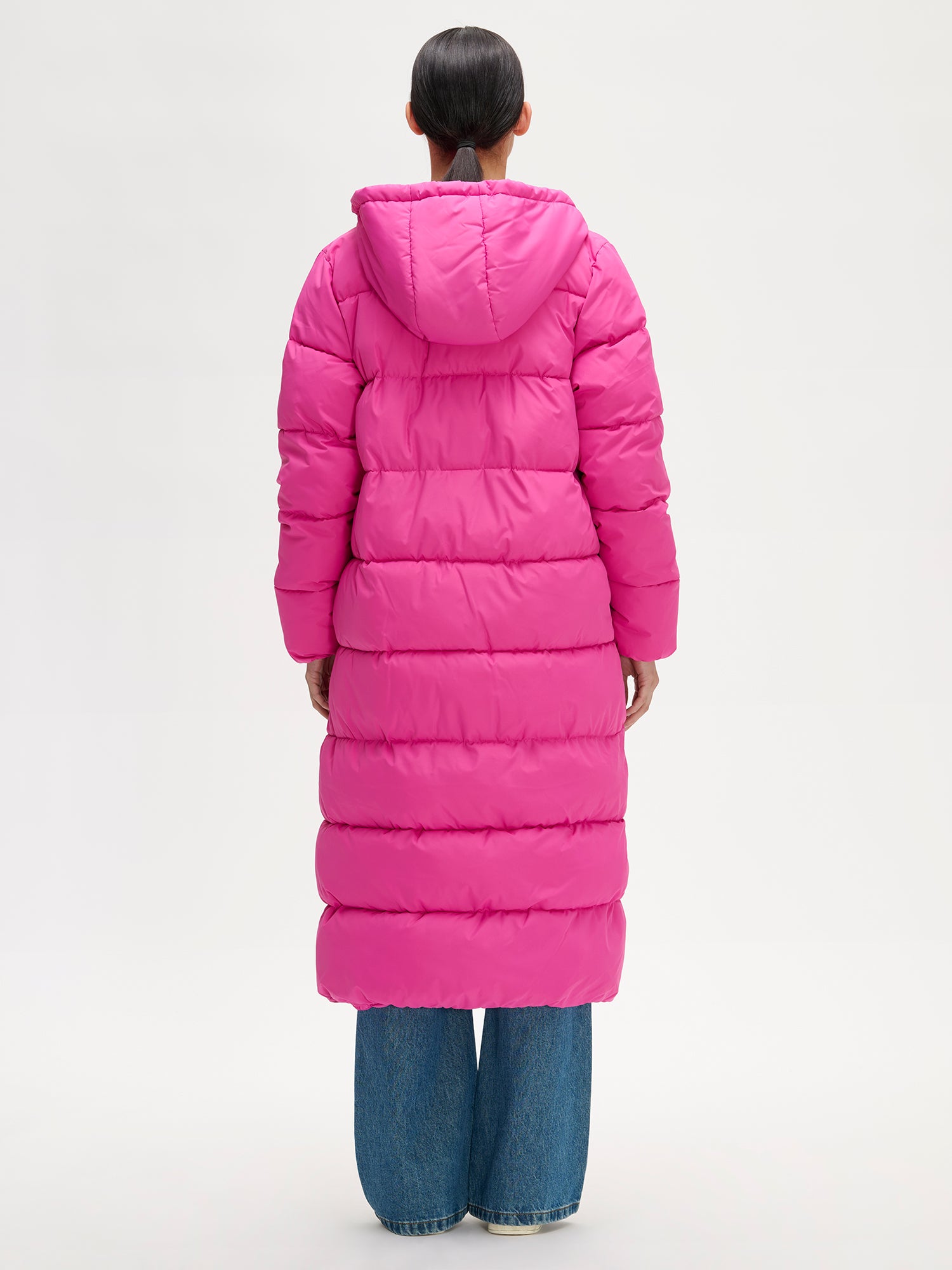 Nanso women´s Lumi Long Pink Puffer Coat in pink offers cozy warmth with its lightweight, puffy insulation. Worn by a model from the back.
