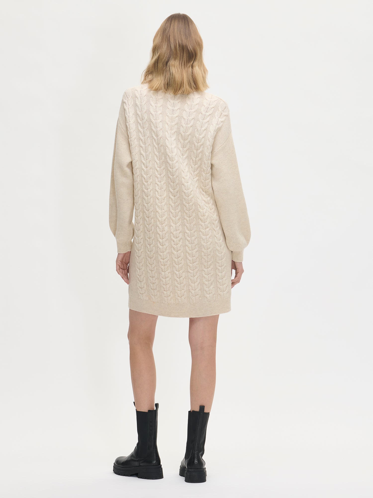 Person wearing a beige quilted dress on a white background