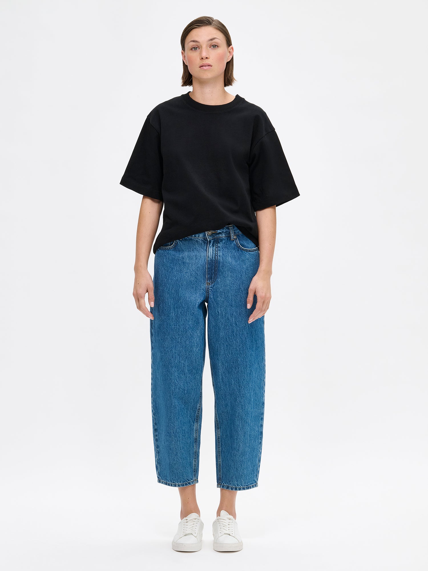 Nanso women's solid black Forma T-shirt. This boxy, loose-fitting T-shirt features a round ribbed neckline and loose 2/4-length sleeves. On a model with relaxed jeans.