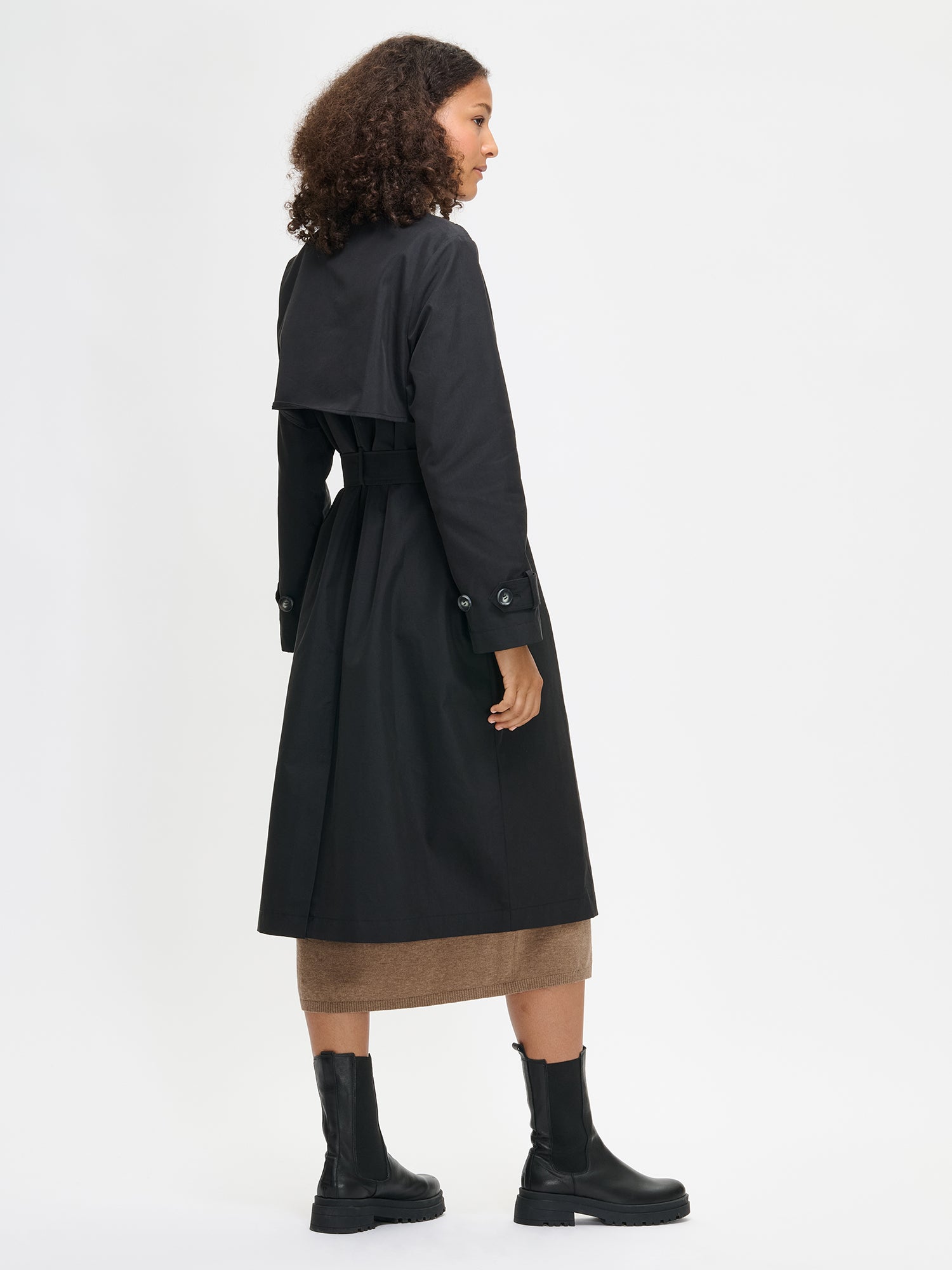 Woman wearing a black trench coat on a white background