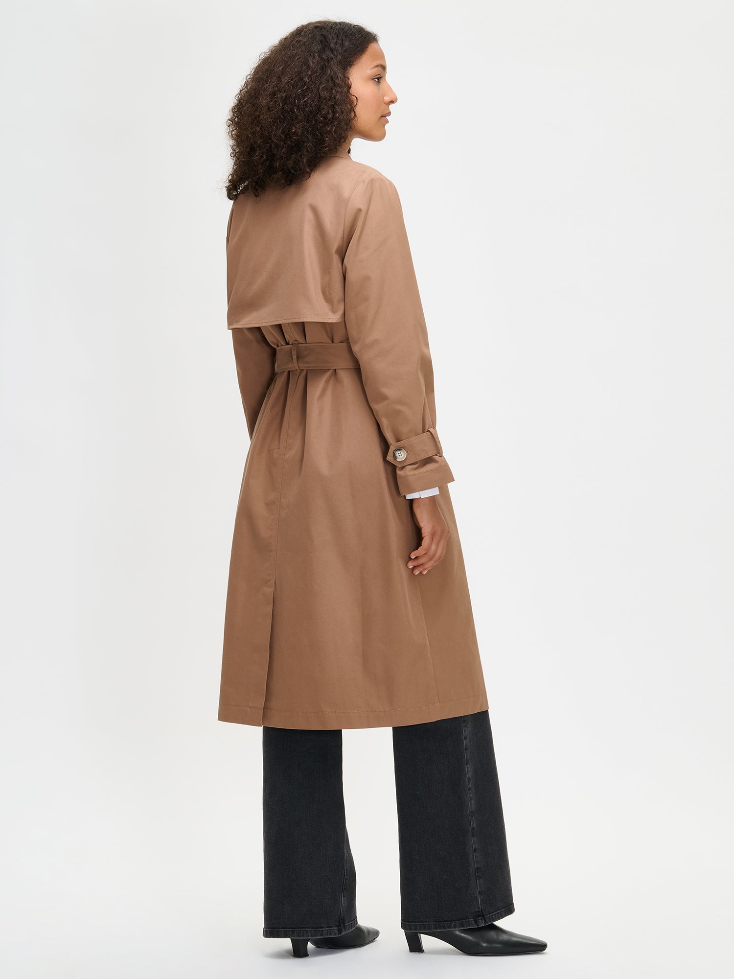Woman wearing a brown trench coat on a white background