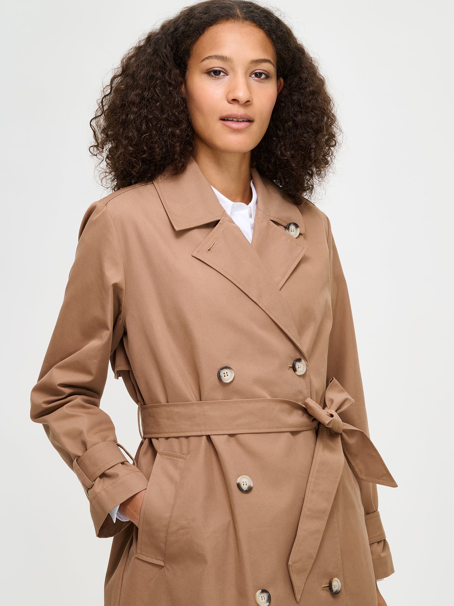 Woman wearing a brown trench coat on a white background
