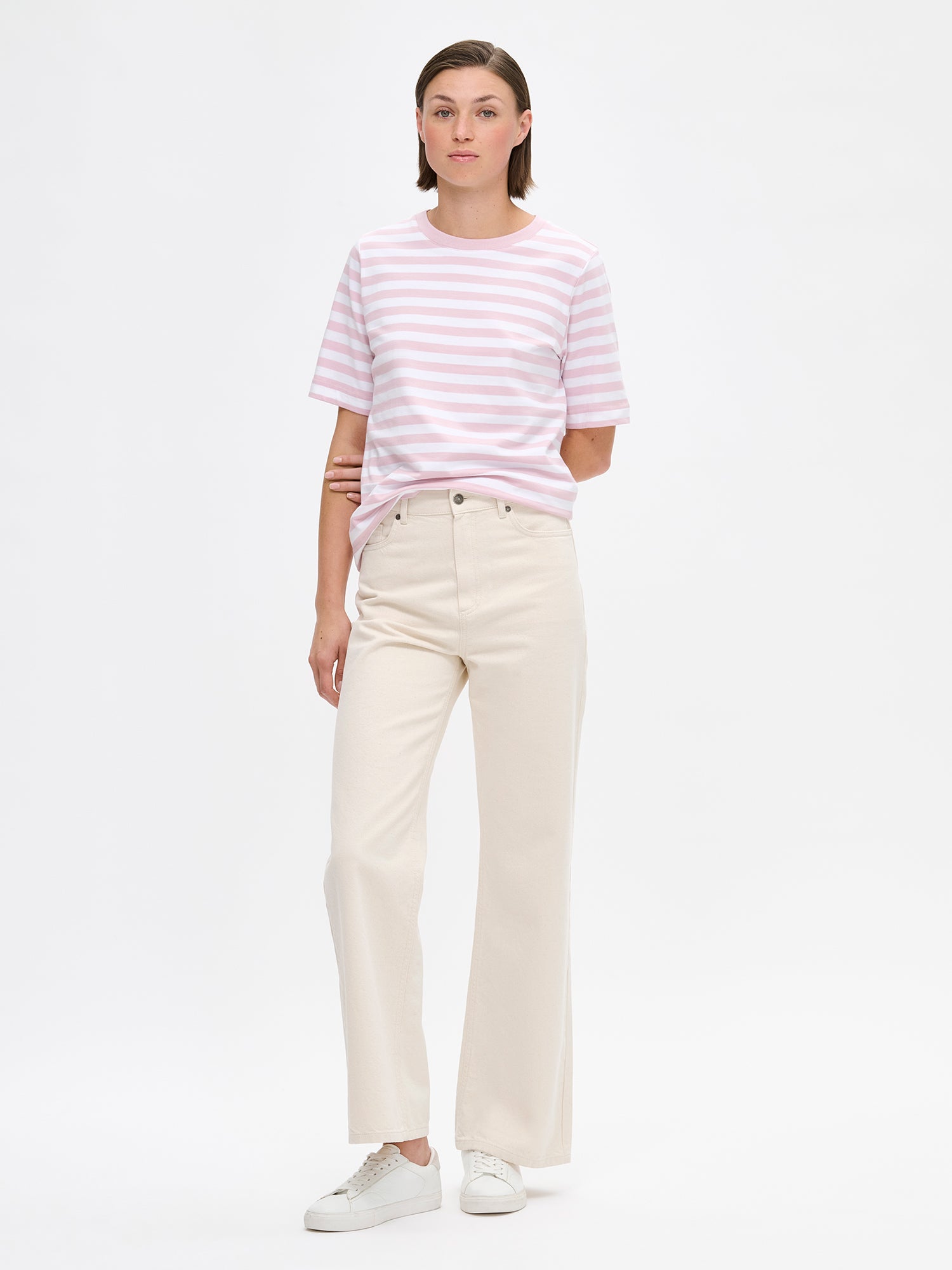 Women's Normi striped T-shirt in Pink with relaxed fit and straightforward silhouette. The material is 100% high-quality organic cotton, which maintains its quality over time. on a model with jeans.