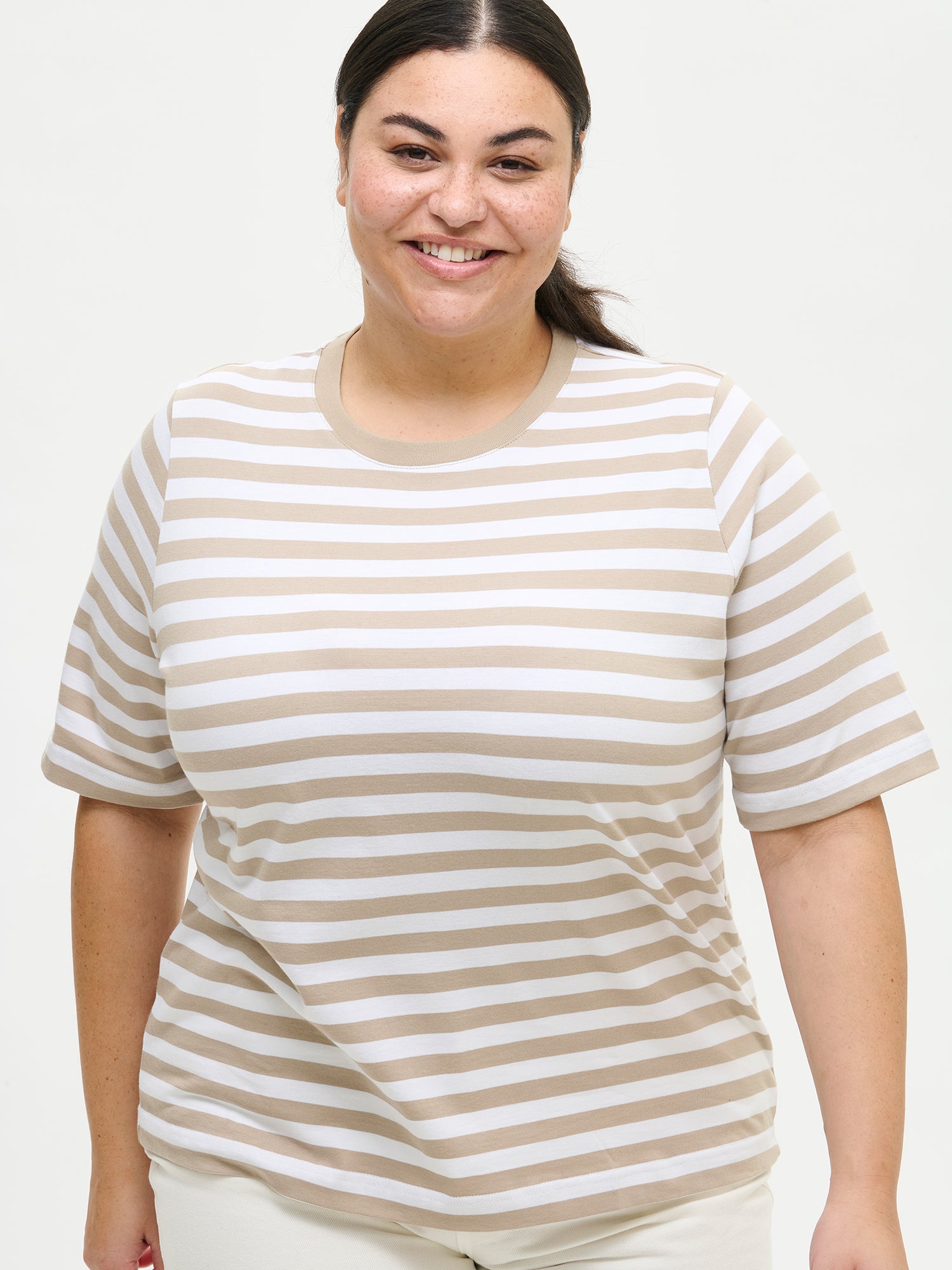 This striped beige and white Raita Normi t-shirt for women is a comfortable everyday classic, perfect for wearing day after day. Worn by a model in size XL from the front.