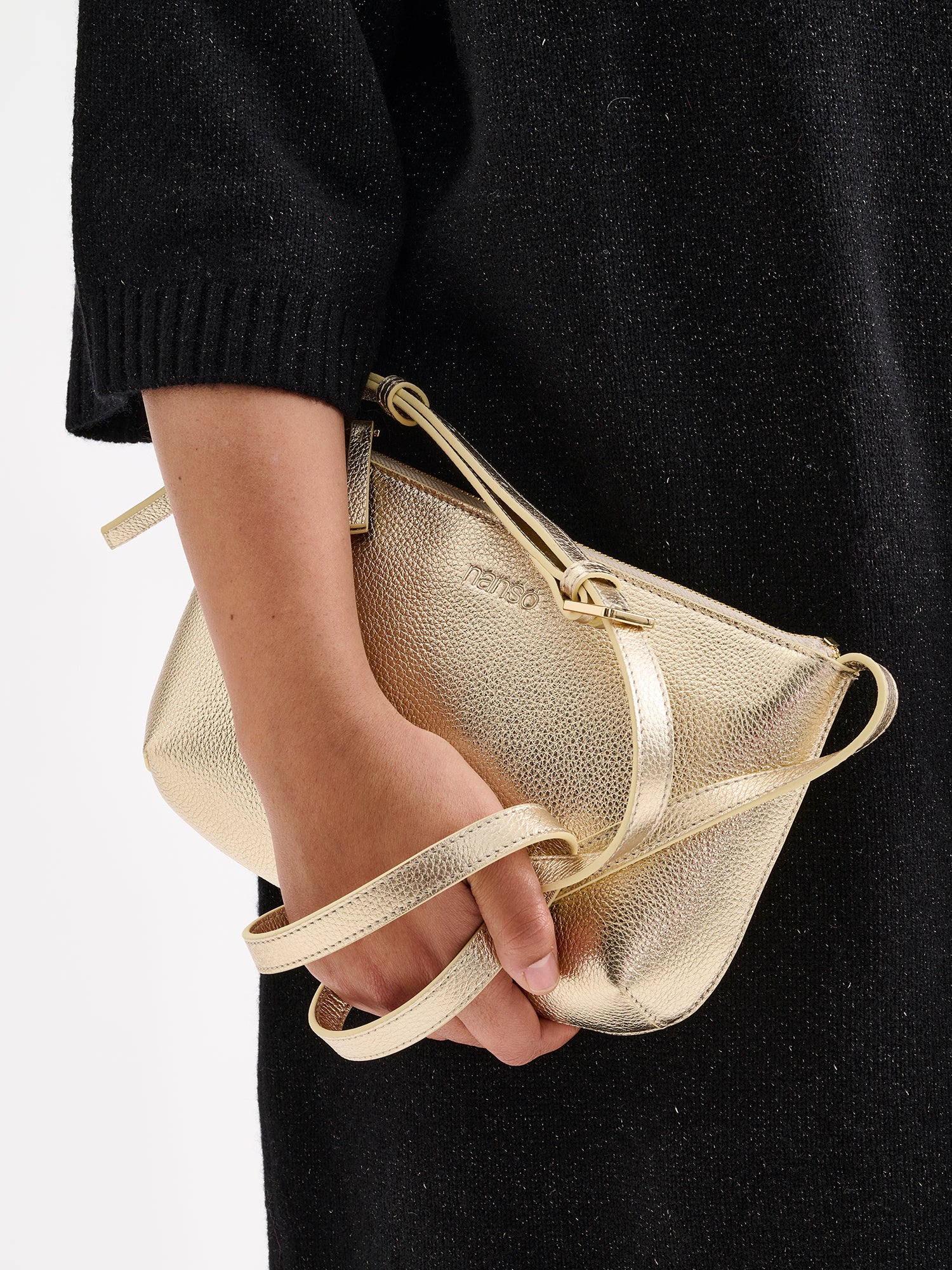 Nanso sleek Naru leather bag in gold pictured in a models hand