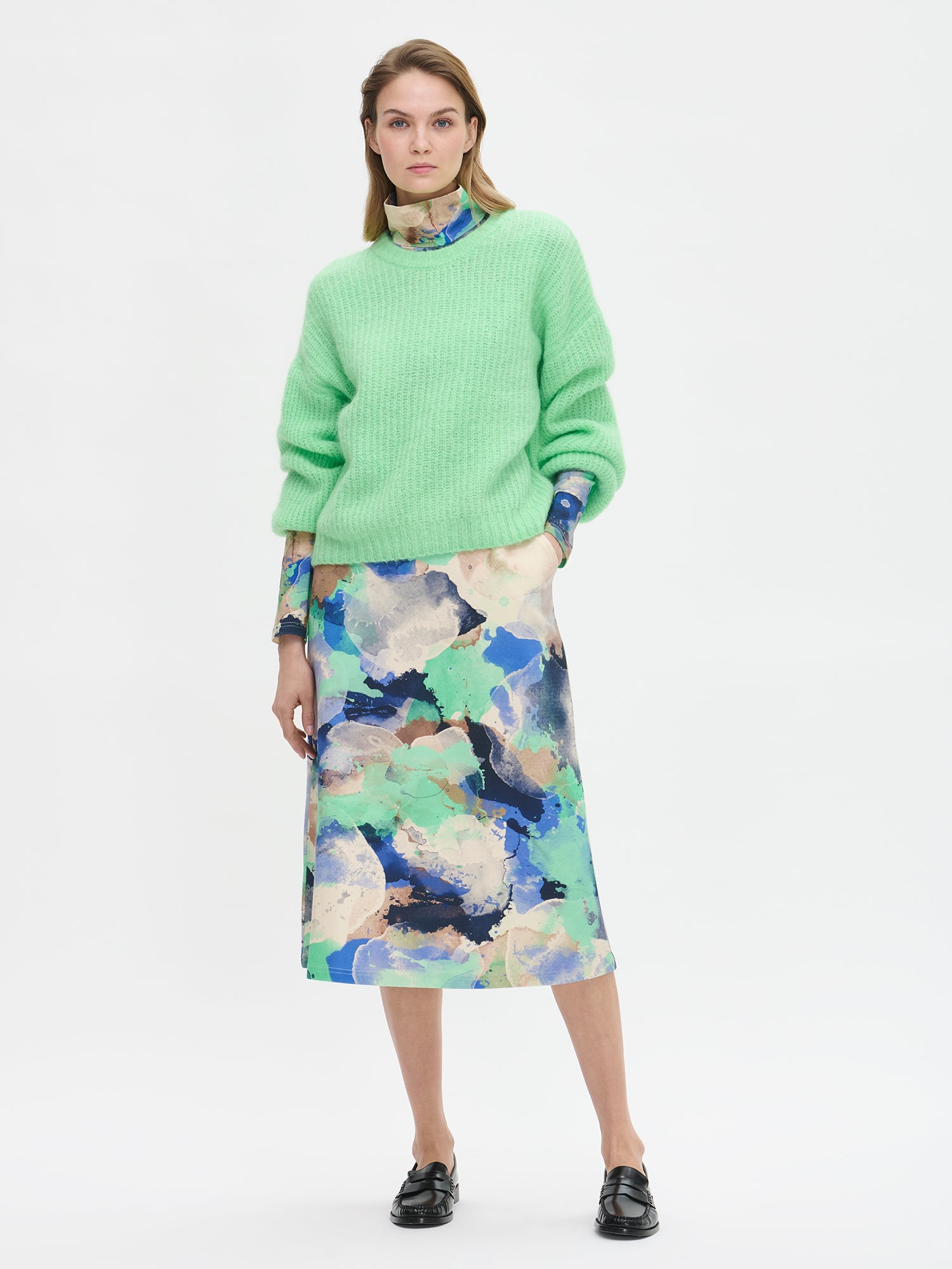 KARAMELLI women's luxurious mohair blend Knit Sweater in light green shade features a round neckline and full-length sleeves. Pictured on a model with a patterned dress.