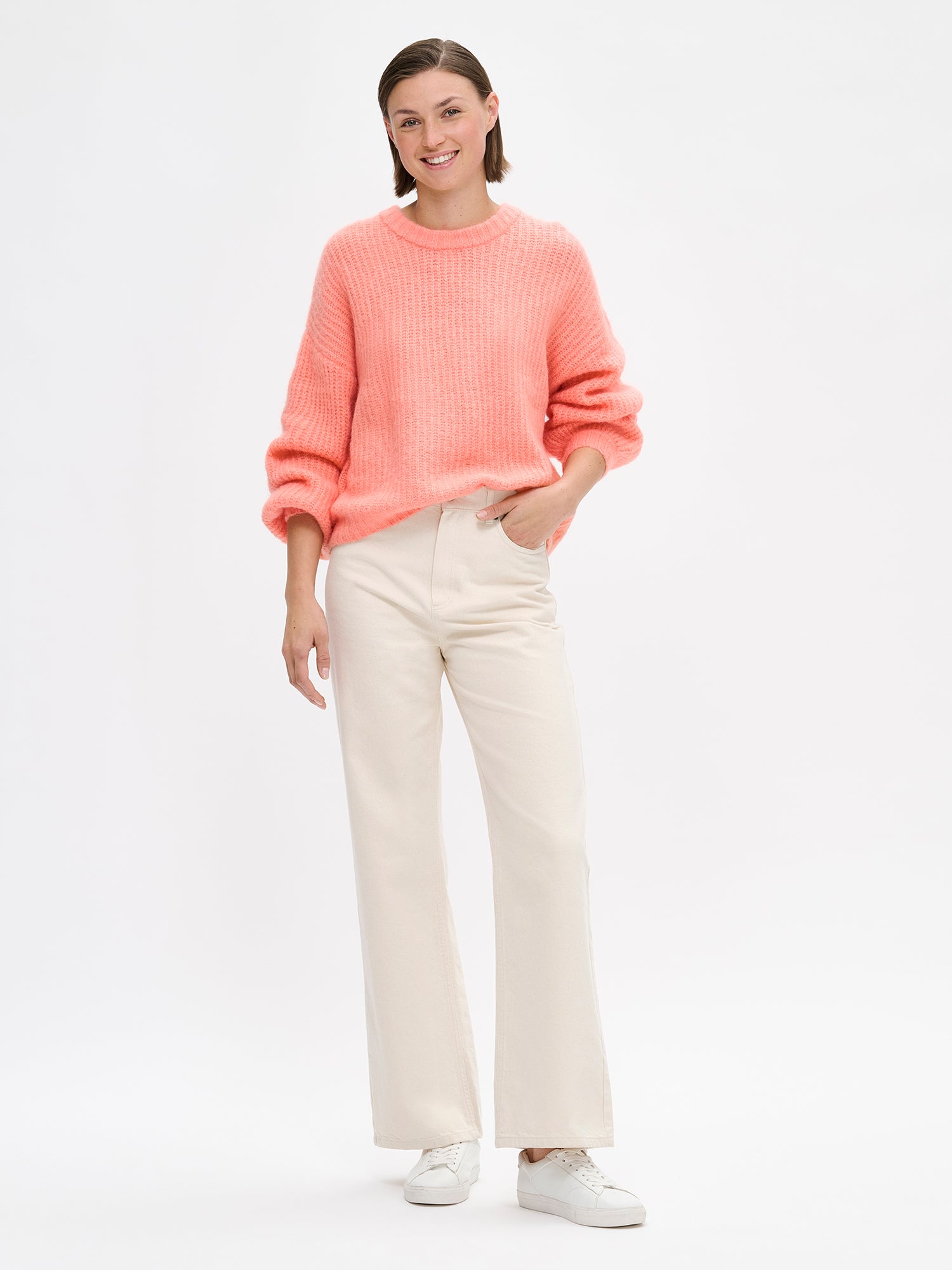 KARAMELLI women's luxurious mohair blend Knit Sweater in coral shade features a round neckline and full-length sleeves. On a model with jeans.