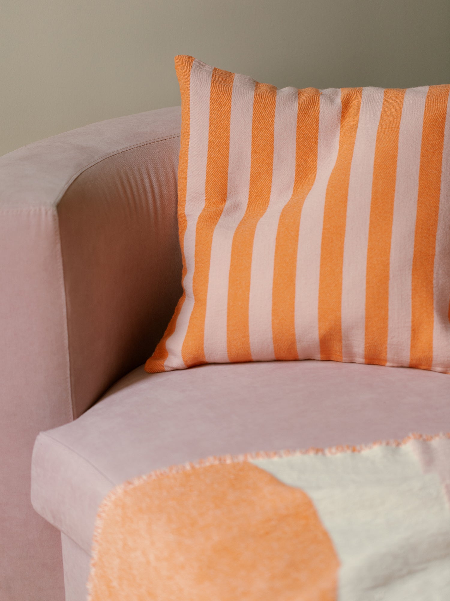 Nanso home's Kuutio pillow case in orange from front in stripe on sofa.