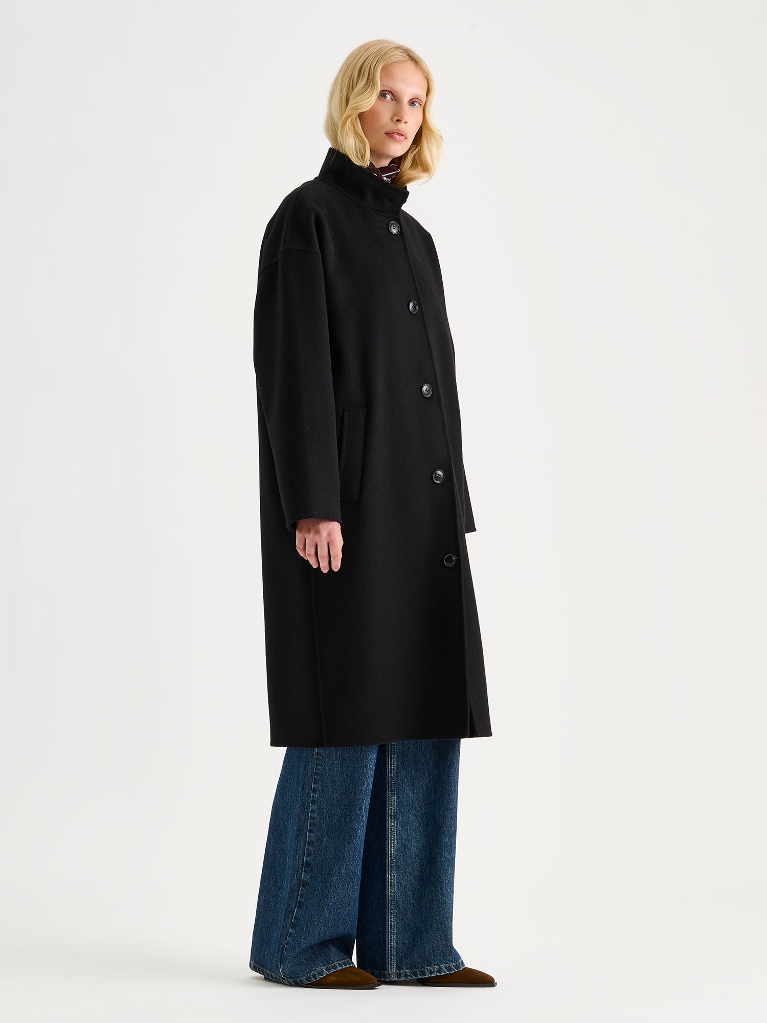 Nanso women's long black Elle wool coat on a blonde model with blue jeans.