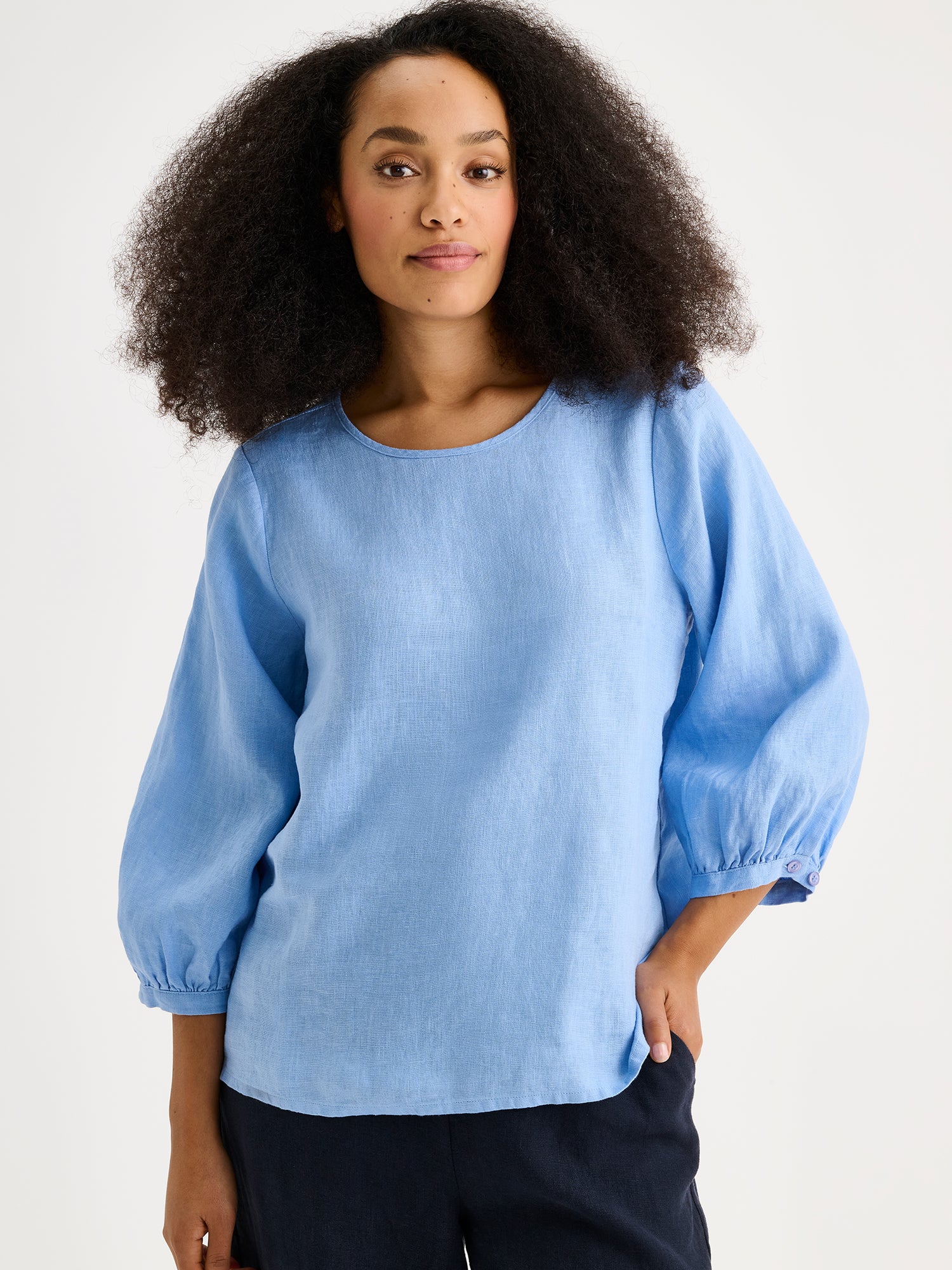 Nanso women's Saralia linen Blouse in blue on a model with dark blue linen trousers, close-up.