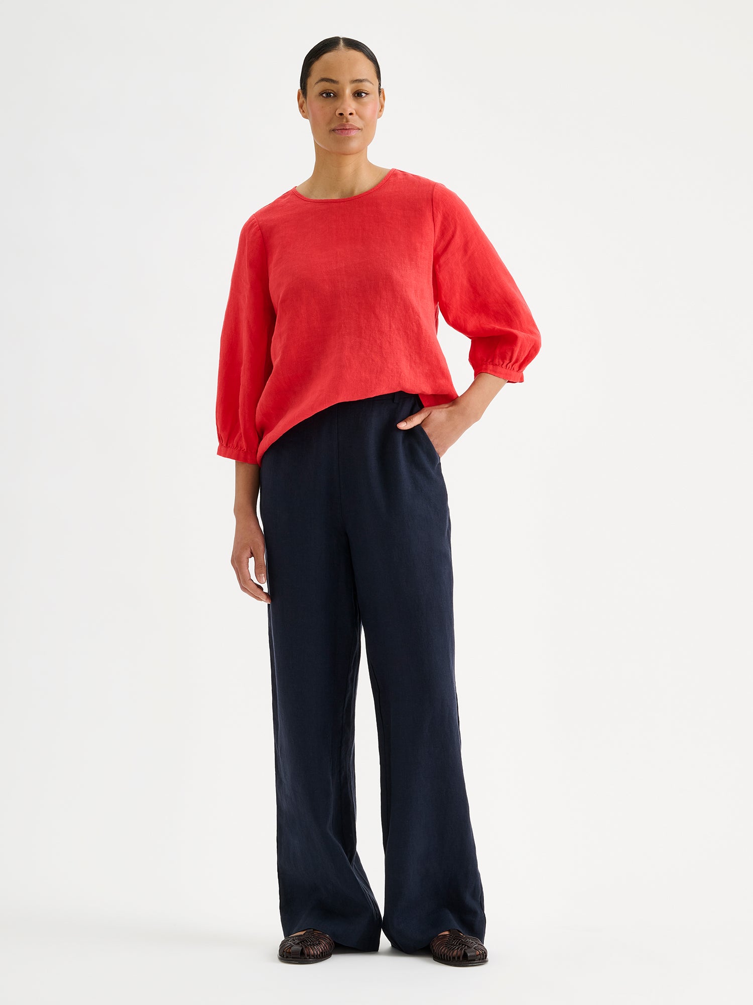 Nanso women's Saralia linen Blouse in red on a model with dark linen trousers.