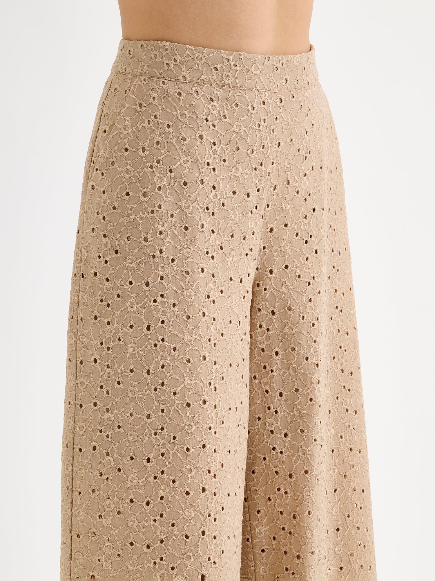 Nanso women's beige embroidered Nuppu trousers with a broderie anglais style lace fabric on a model, close-up.