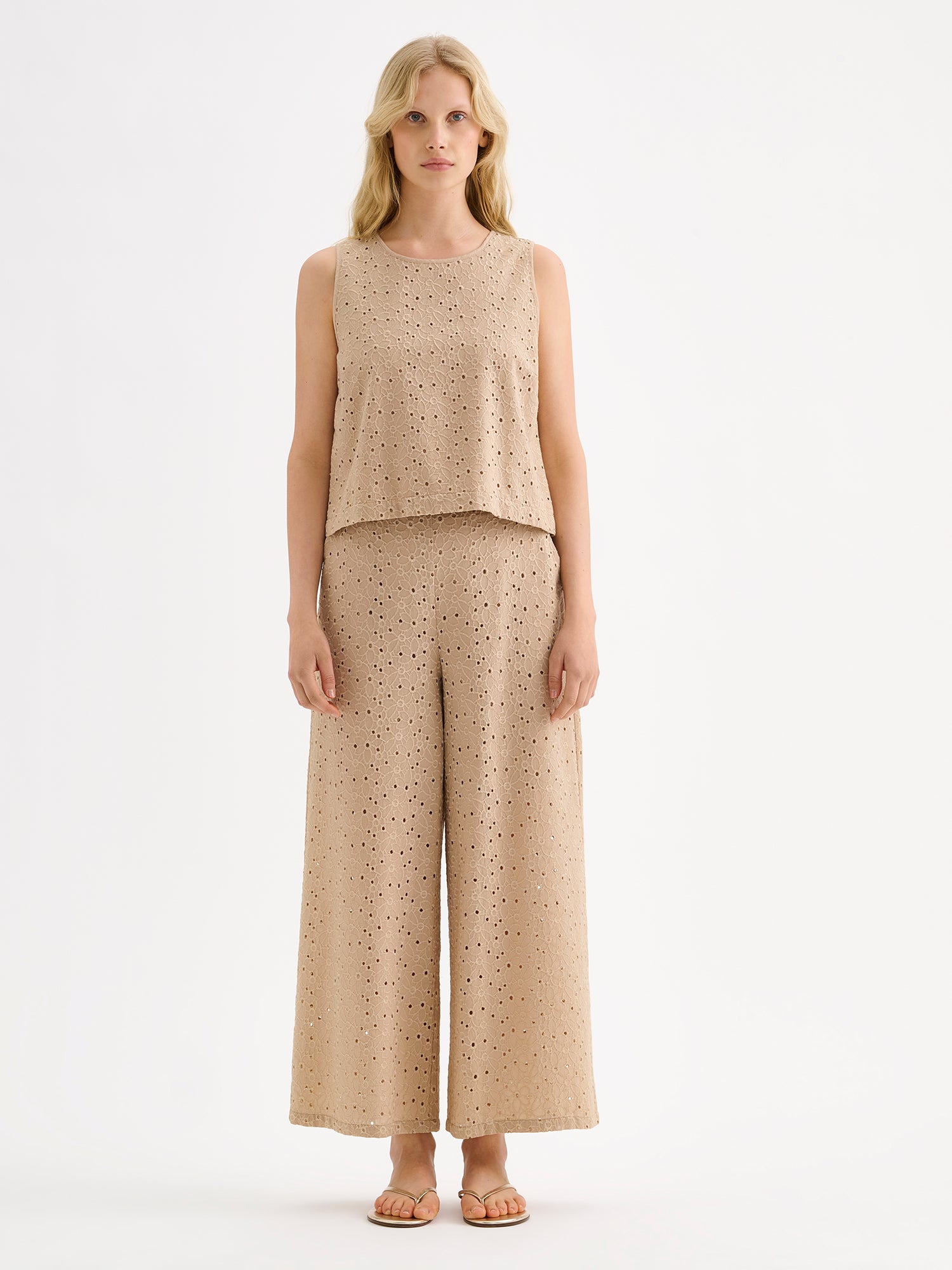 Nanso women's beige embroidered Nuppu trousers with a broderie anglais style lace fabric on a model with a matching top.