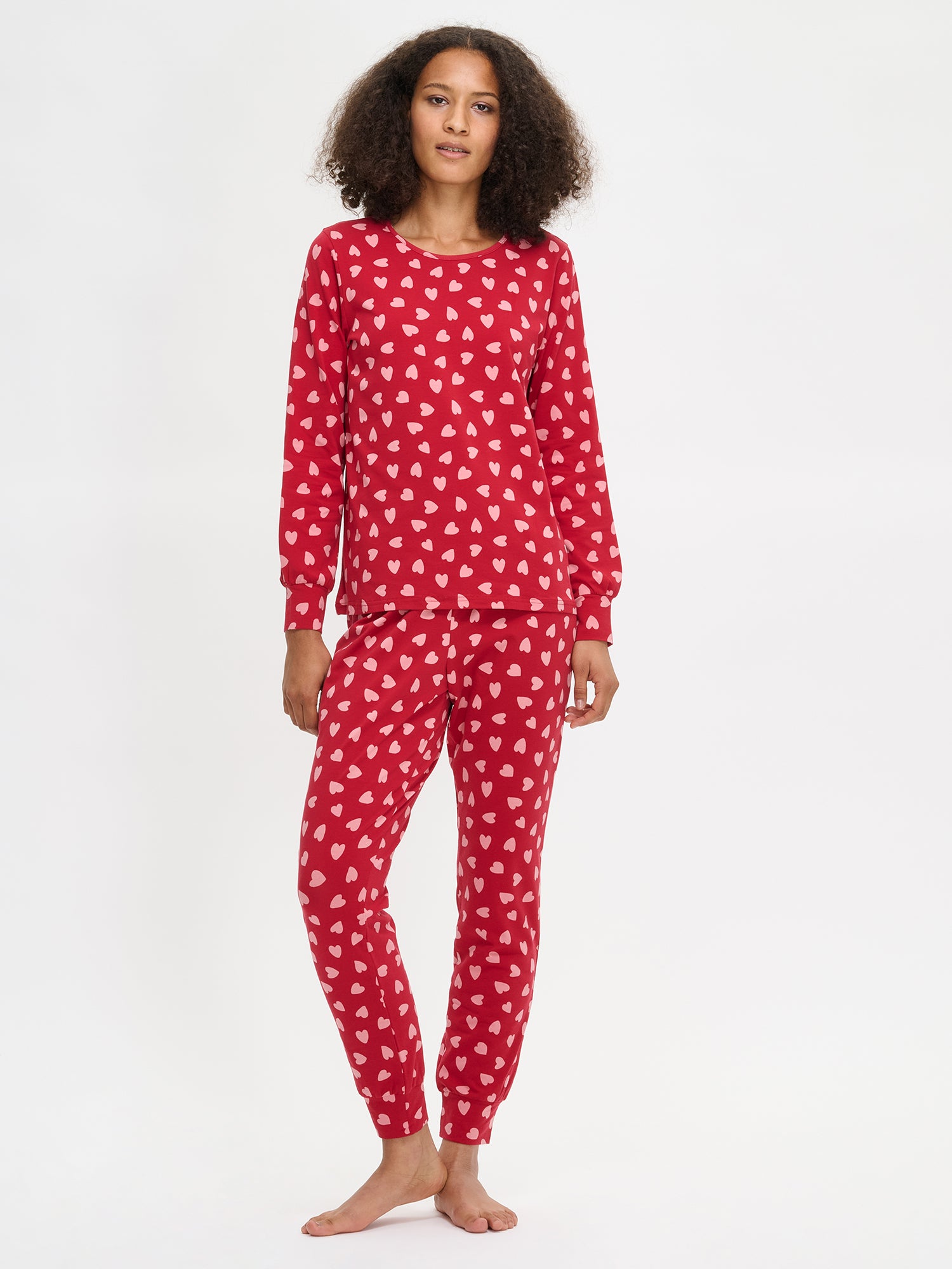Nanso women's Amor red pyjamas with a joyful patterned design, round neckline and long sleeves, on a model from the front.