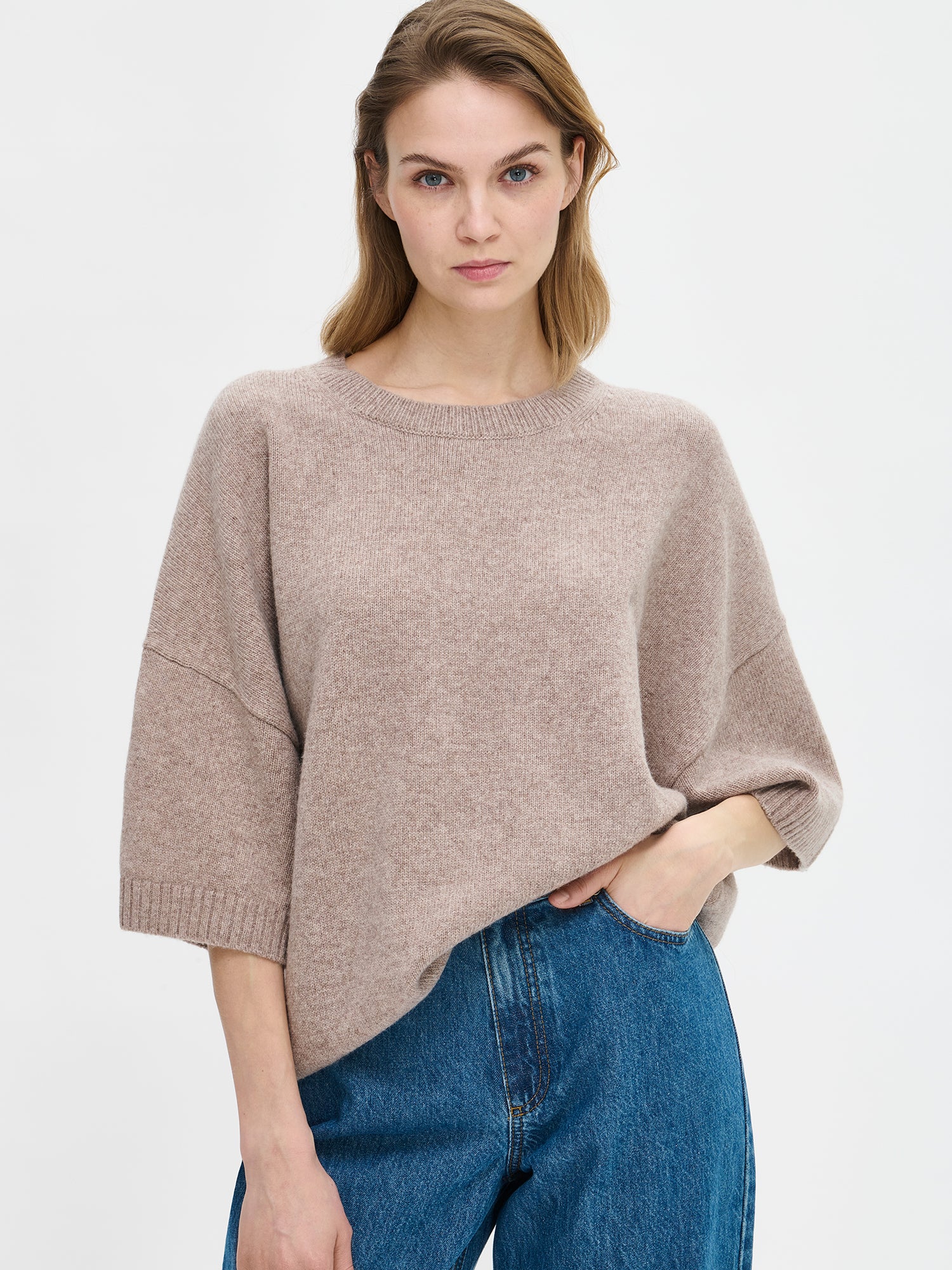 Women's Lana knit sweater in greige features relaxed, oversize silhouette, a classic crew neckline and 1/2 sleeves. On a model from the front, close-up.