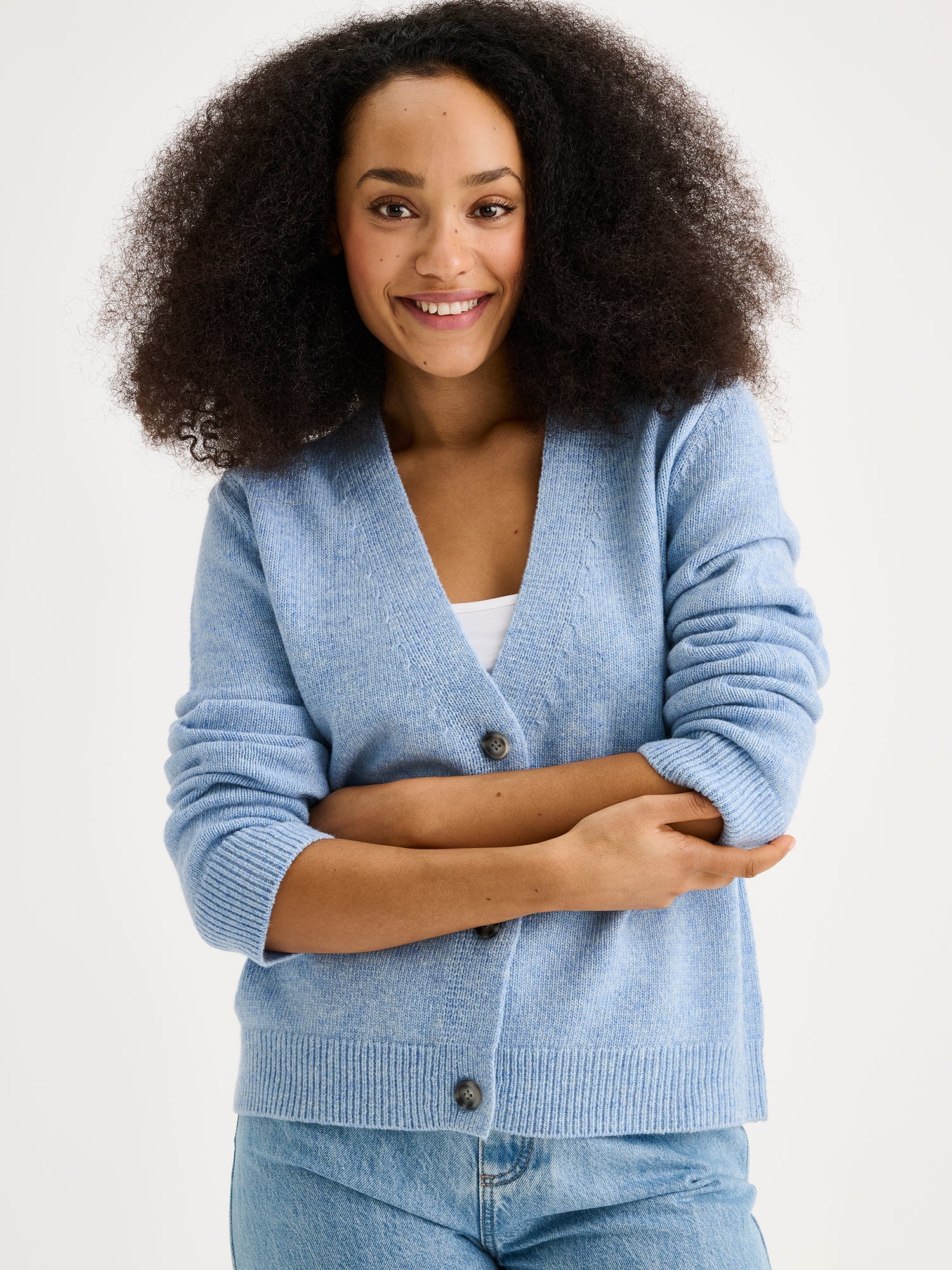 The LANA long-sleeved Knit Cardigan in blue with a flattering V-neckline and button closure down the front. On a model with jeans, close-up.