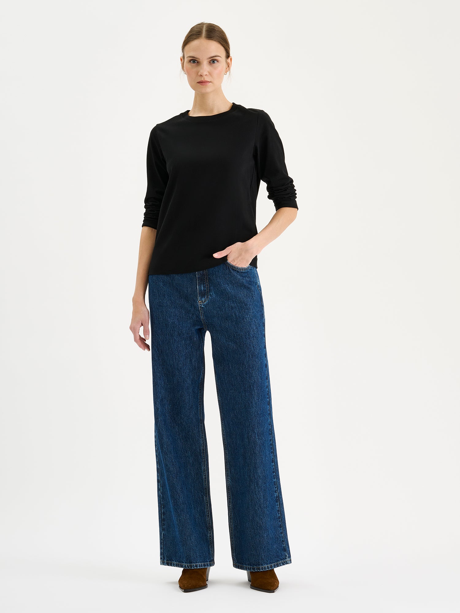Nanso womens black NORMI Long-Sleeved T-Shirt is a versatile piece that features a classic crew neckline and full-length sleeves for everyday versatility. On a model with blue jeans.