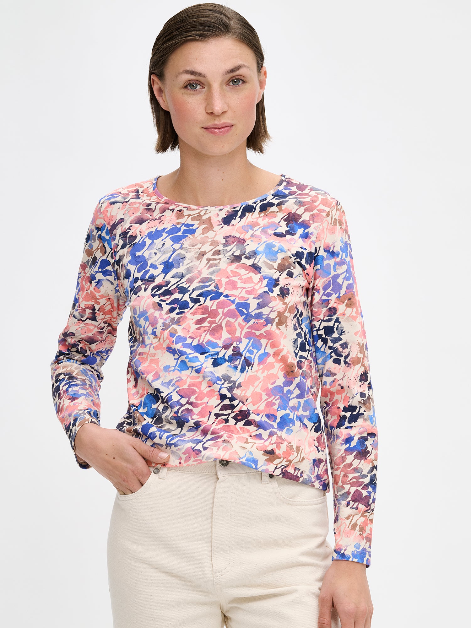 SAGITTA women's patterned blouse. Crafted from soft knit fabric with a clean, straight silhouette with a round neckline finished in ribbed trim and full-length sleeves. On a model pictured from the front, close-up.