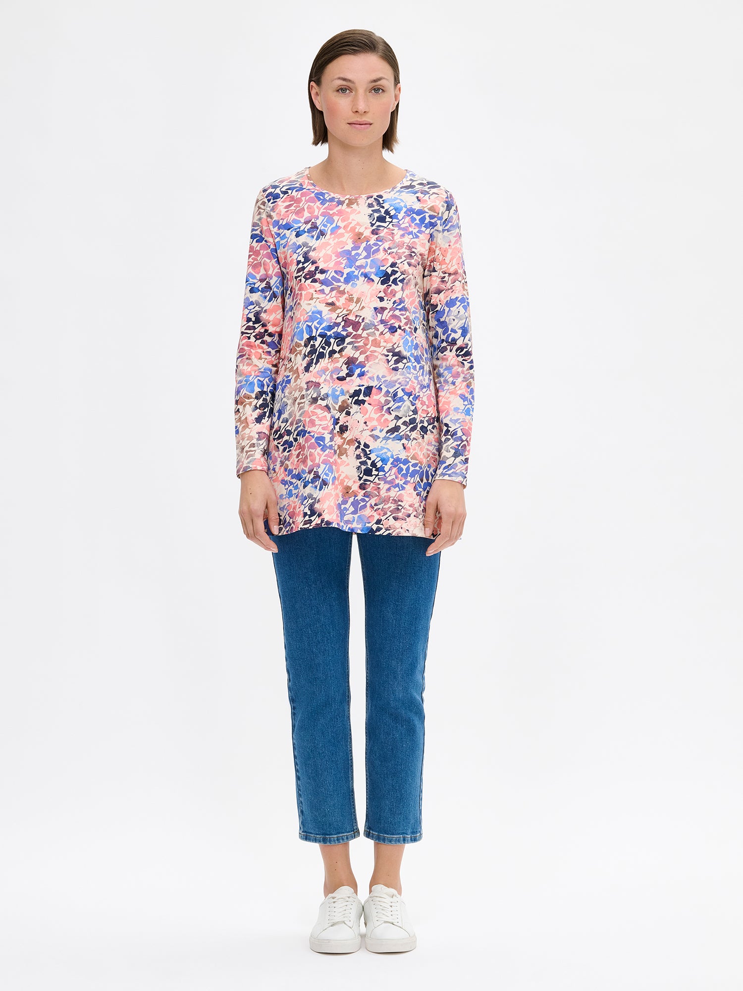 Sagitta women's tunic from soft patterned knit fabric. The tunic features an A-line silhouette, round neckline, side pockets and full-length sleeves. Pictured on a model with jeans and sneakers.