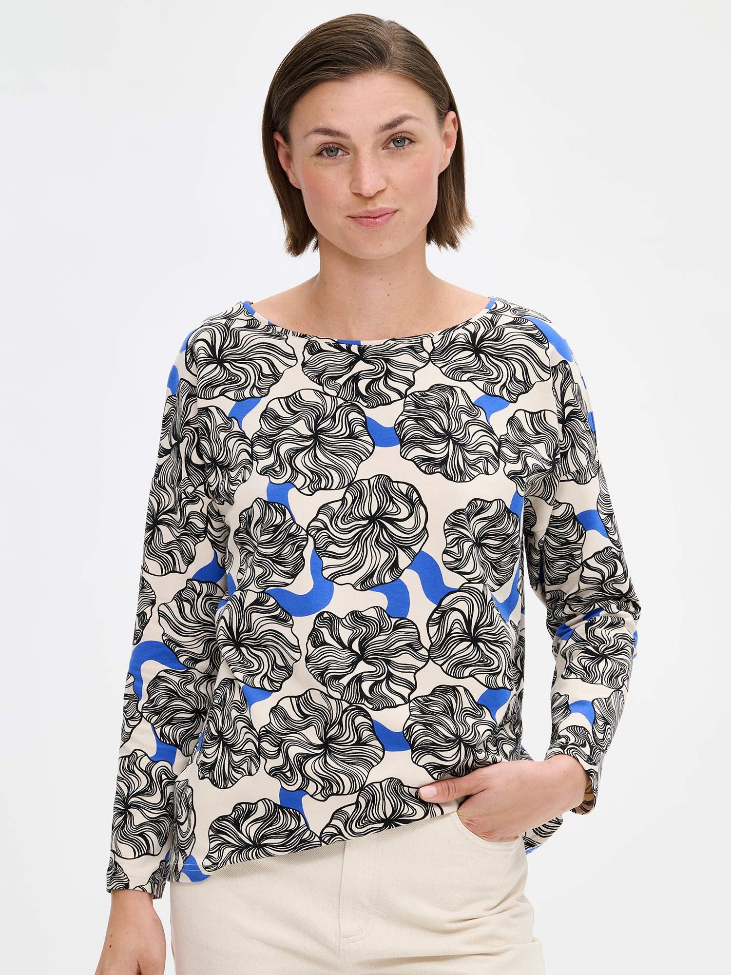 Nanso women's relaxed, patterned Pieni Kosmo blouse. The boxy blouse features a neckline finished with binding and full-length sleeves. The shoulder line is generously dropped. On a model with jeans, close-up.