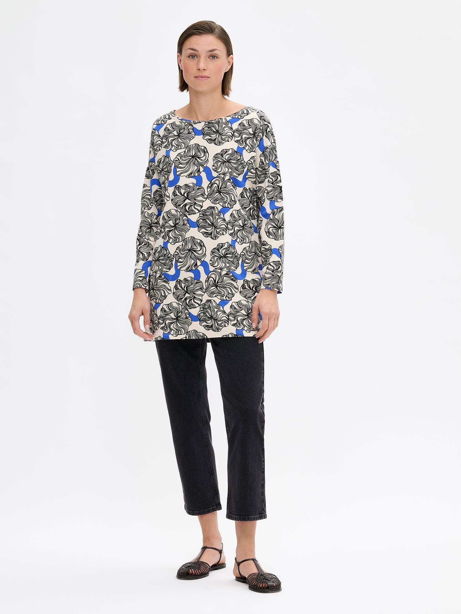 Nanso women's versatile, patterned Pieni Kosmo tunic. The straight-cut tunic features a dropped shoulder line, side pockets, and full-length sleeves. On a model with jeans.